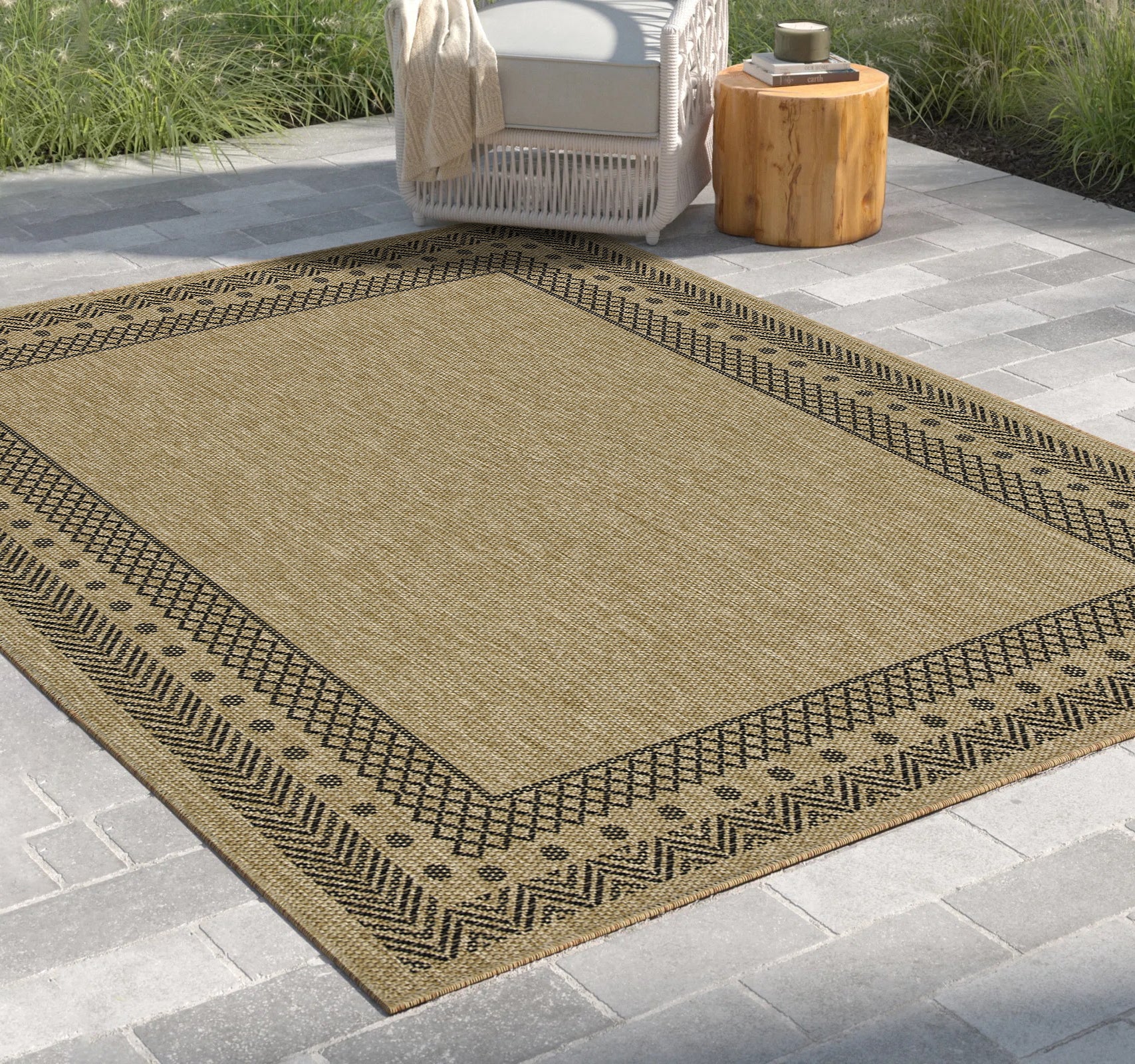 Beige woven outdoor rug with black geometric border pattern