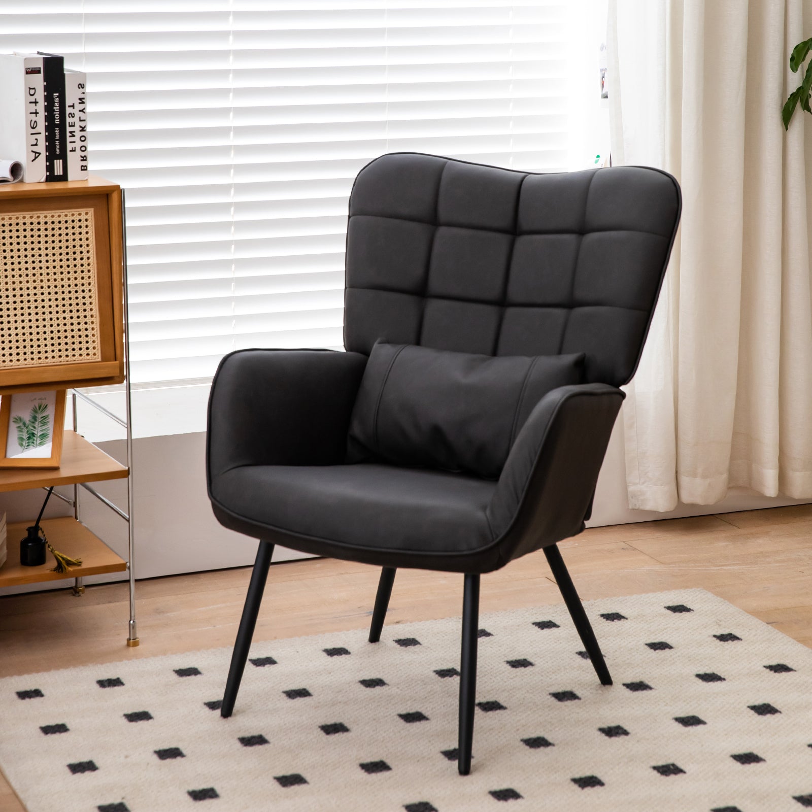 Tufted black faux leather accent chair with pillow and slender black legs