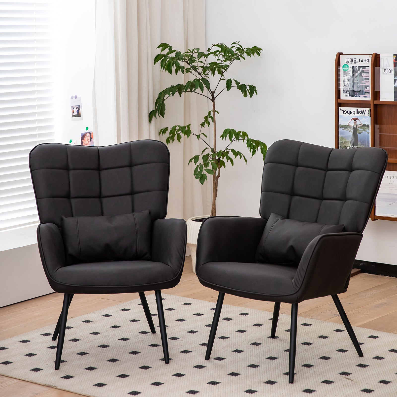 Two black upholstered wingback chairs with tufted backs and lumbar pillows on a patterned rug