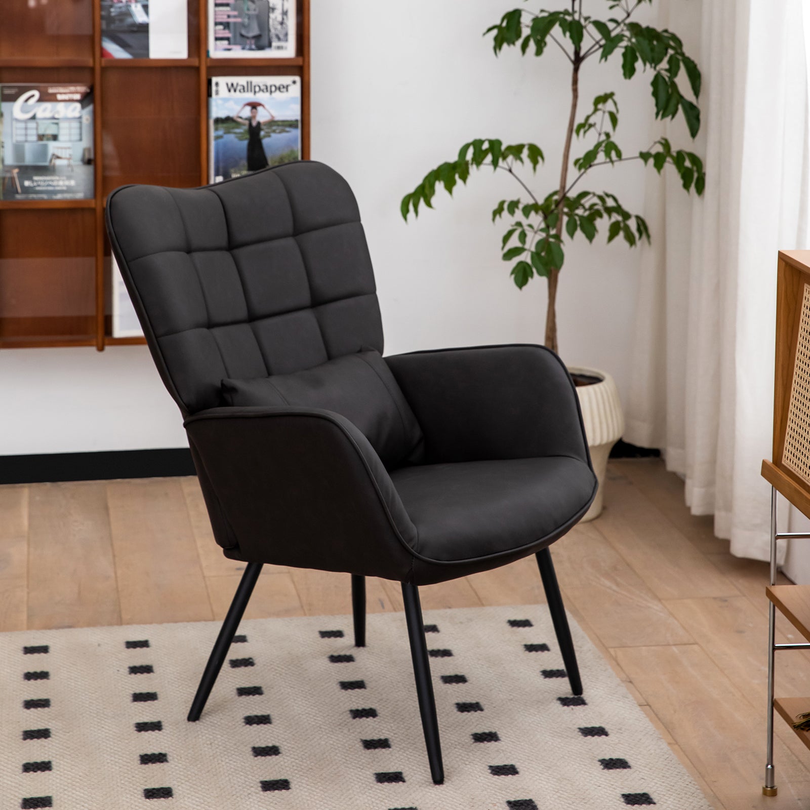 Tufted charcoal armchair with a lumbar pillow and slender black legs perfect for modern living spaces
