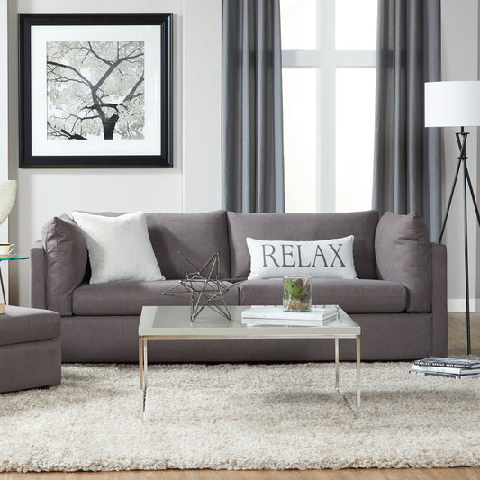 Dark gray fabric sofa with white textured pillow and RELAX lumbar pillow