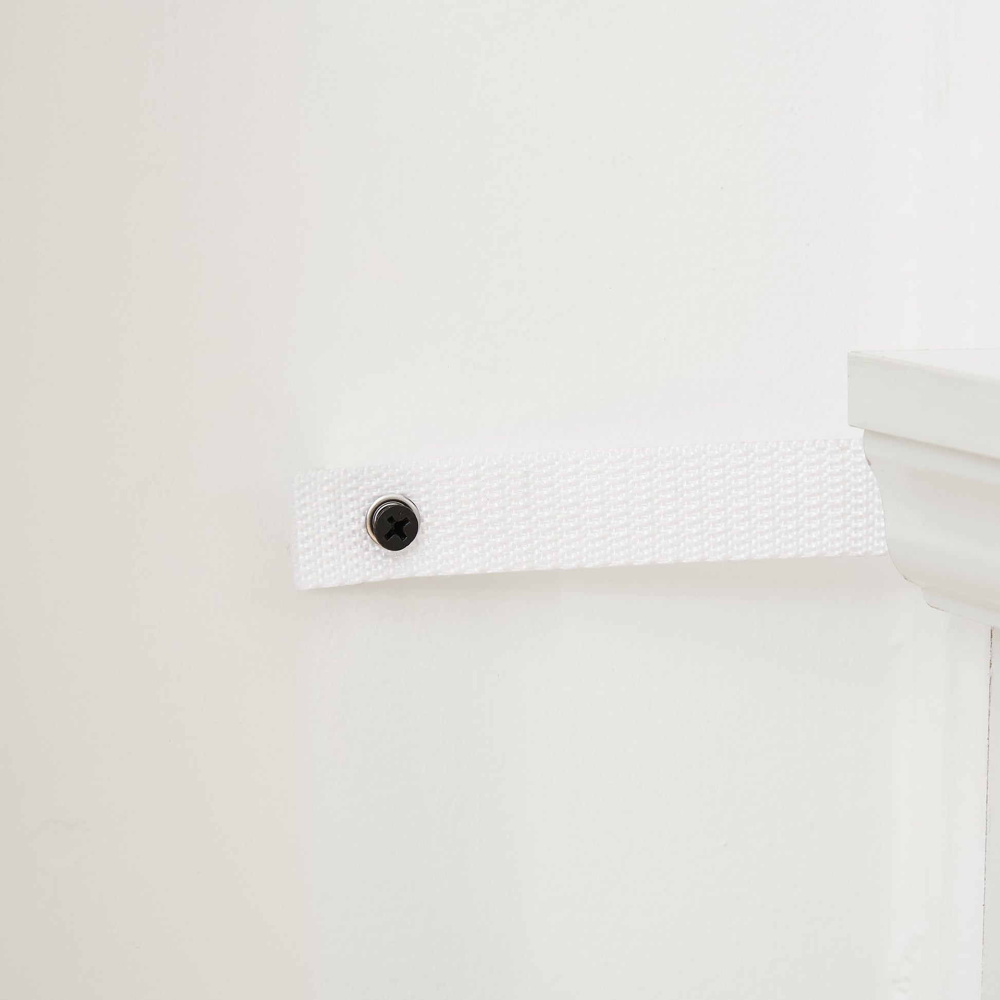 White nylon webbing strap secured with a black screw to a wall