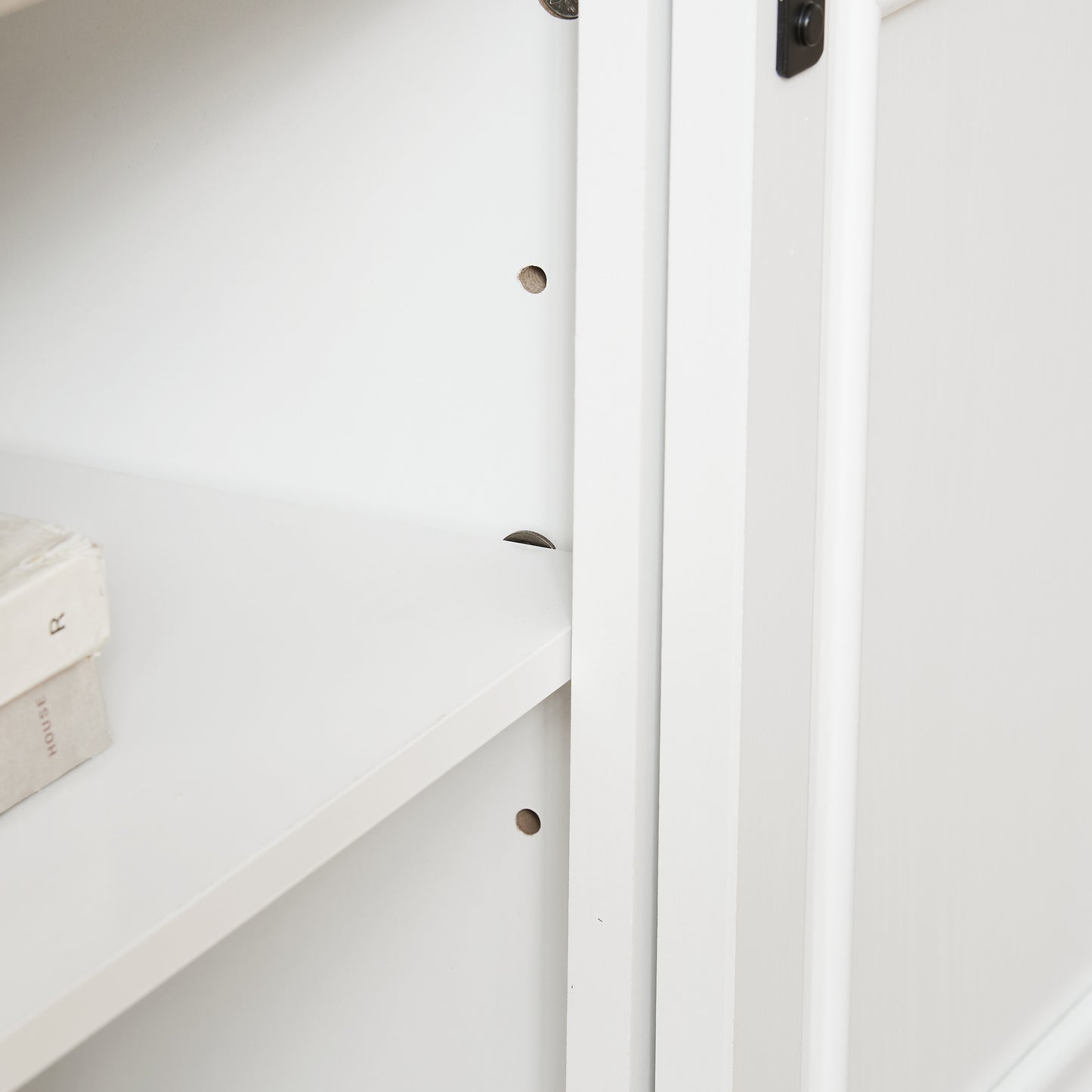 Closeup of a white wooden bookshelf interior with a stack of vintage books