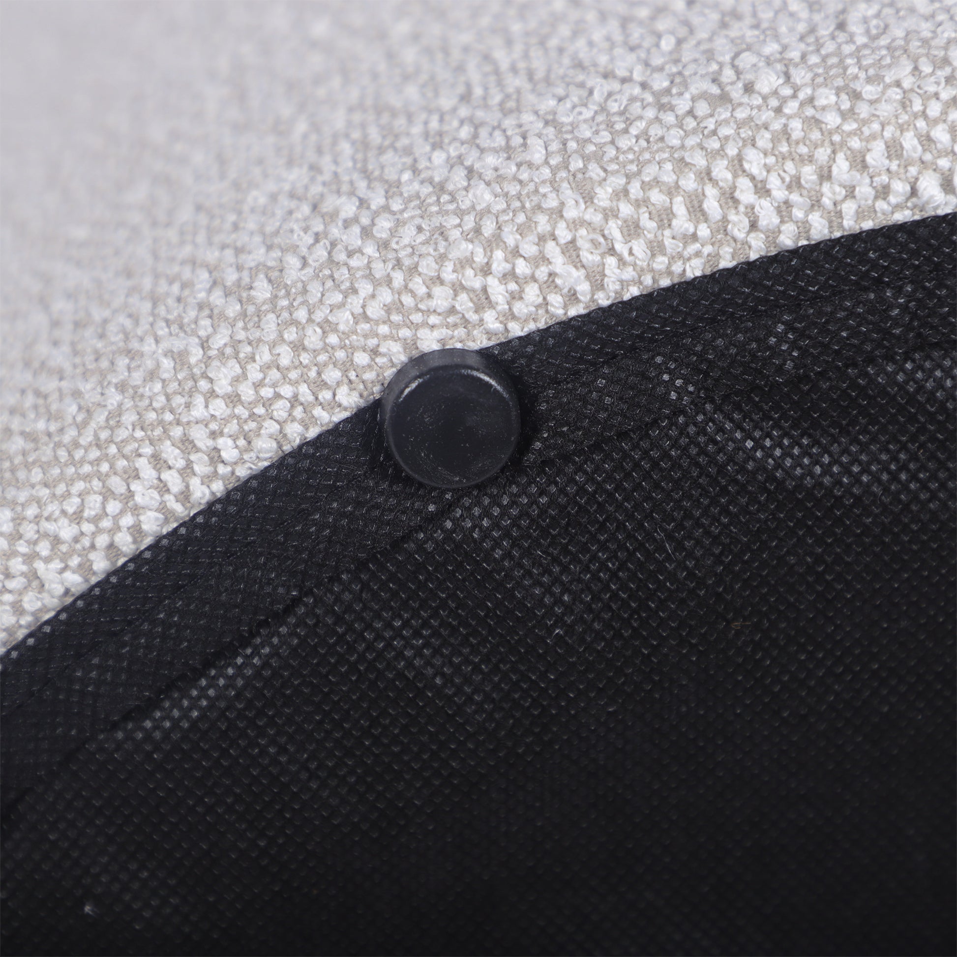 Closeup of a textured light grey fabric with a black plastic foot for furniture stability