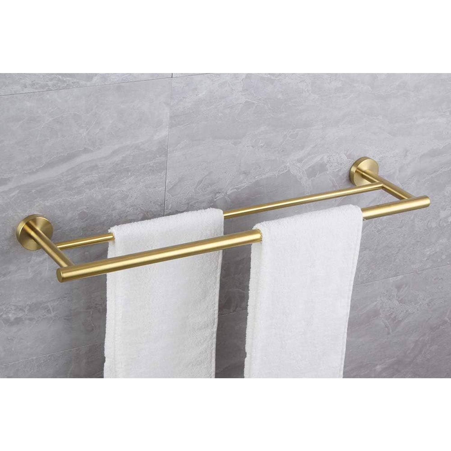 Brushed gold double towel bar holding two white bath towels against marble tile