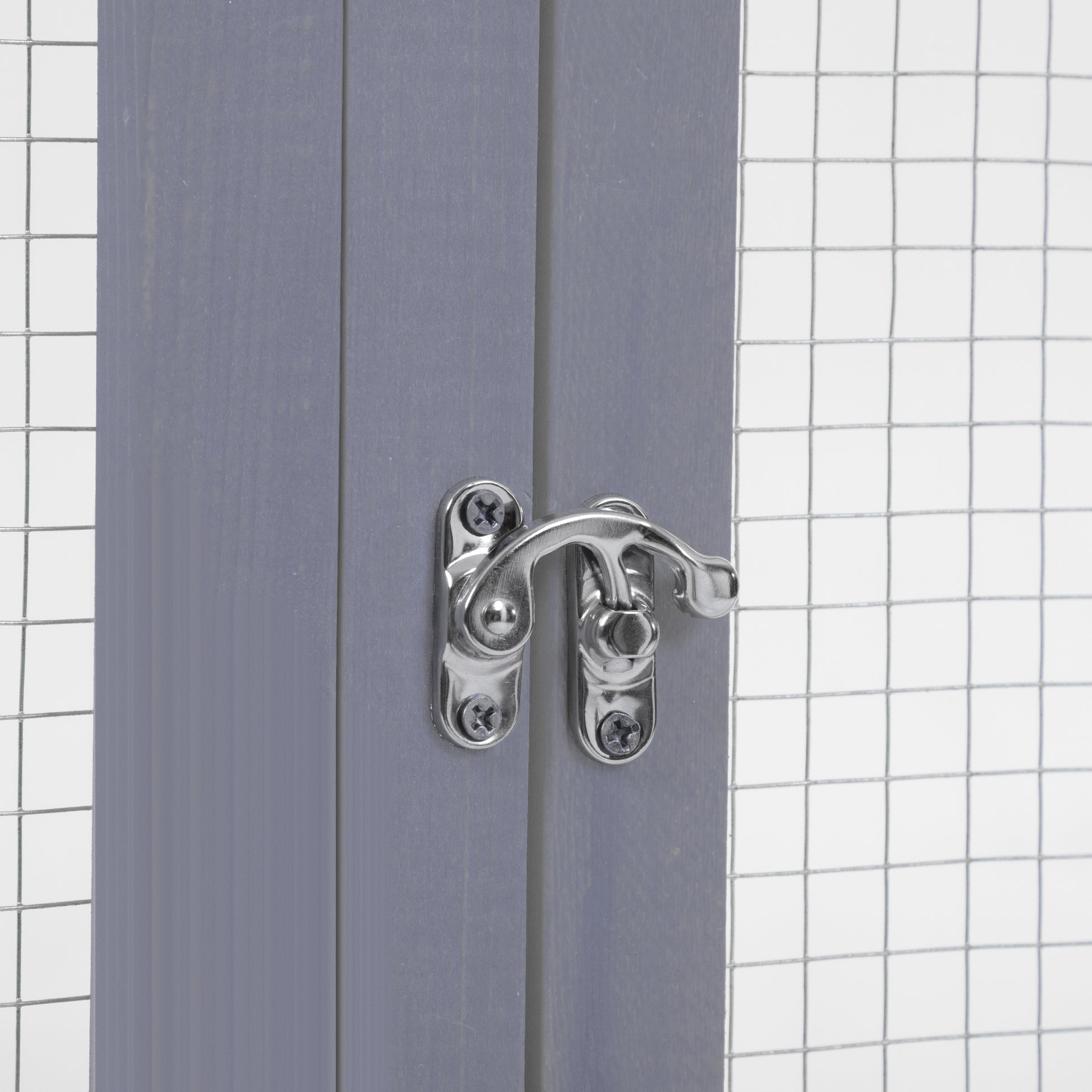 Closeup of a grey wooden pet enclosure with a silver metal latch and wire mesh