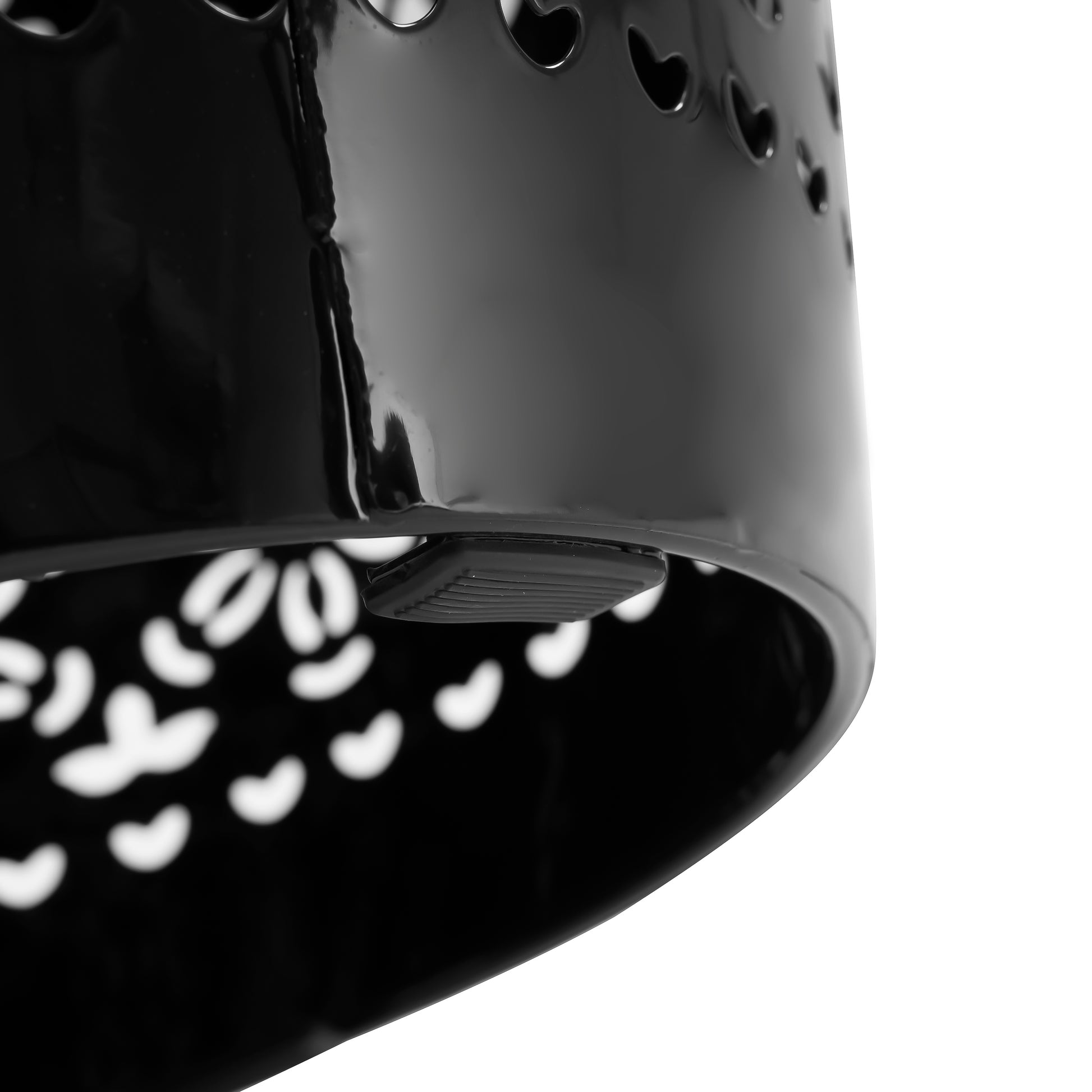 Closeup of a black decorative planter pot with heartshaped cutouts and a raised rim