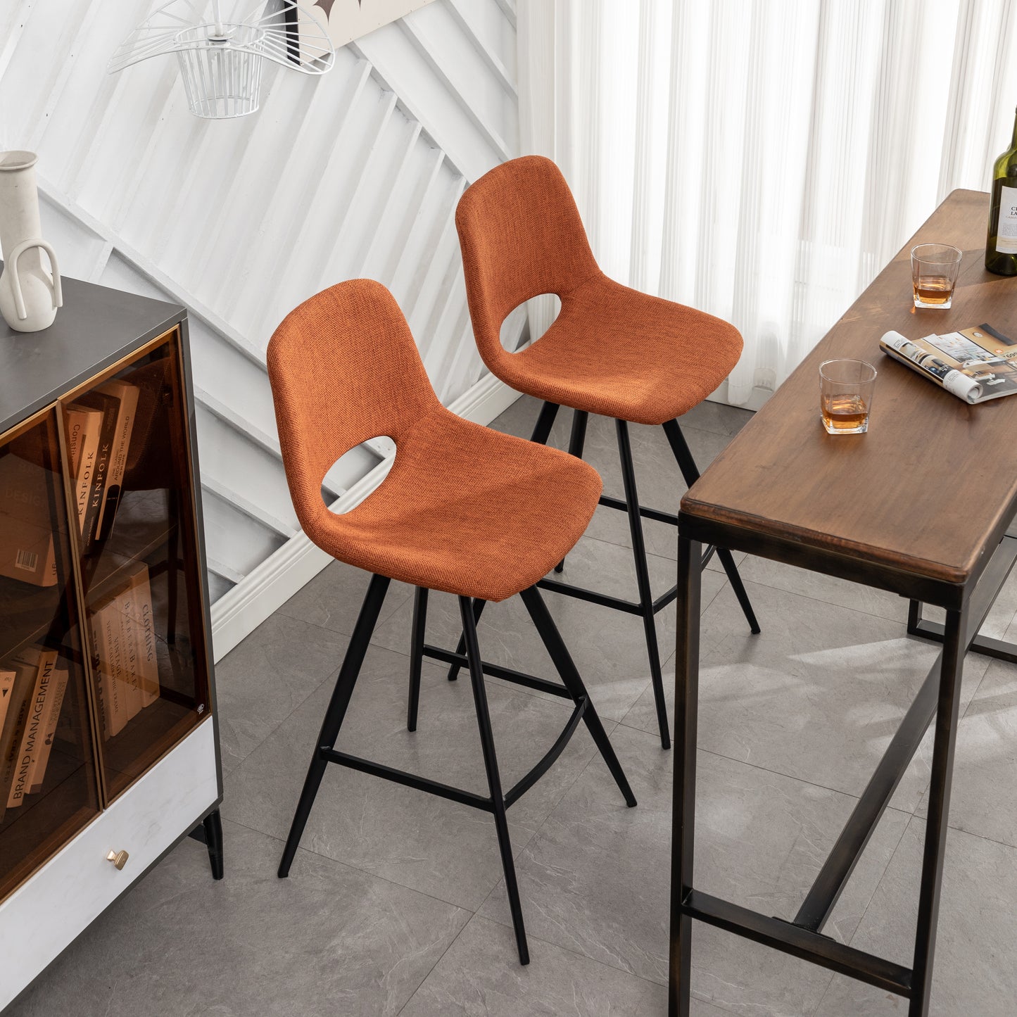 Pair of orange fabric bar stools with cutout backs and black metal legs