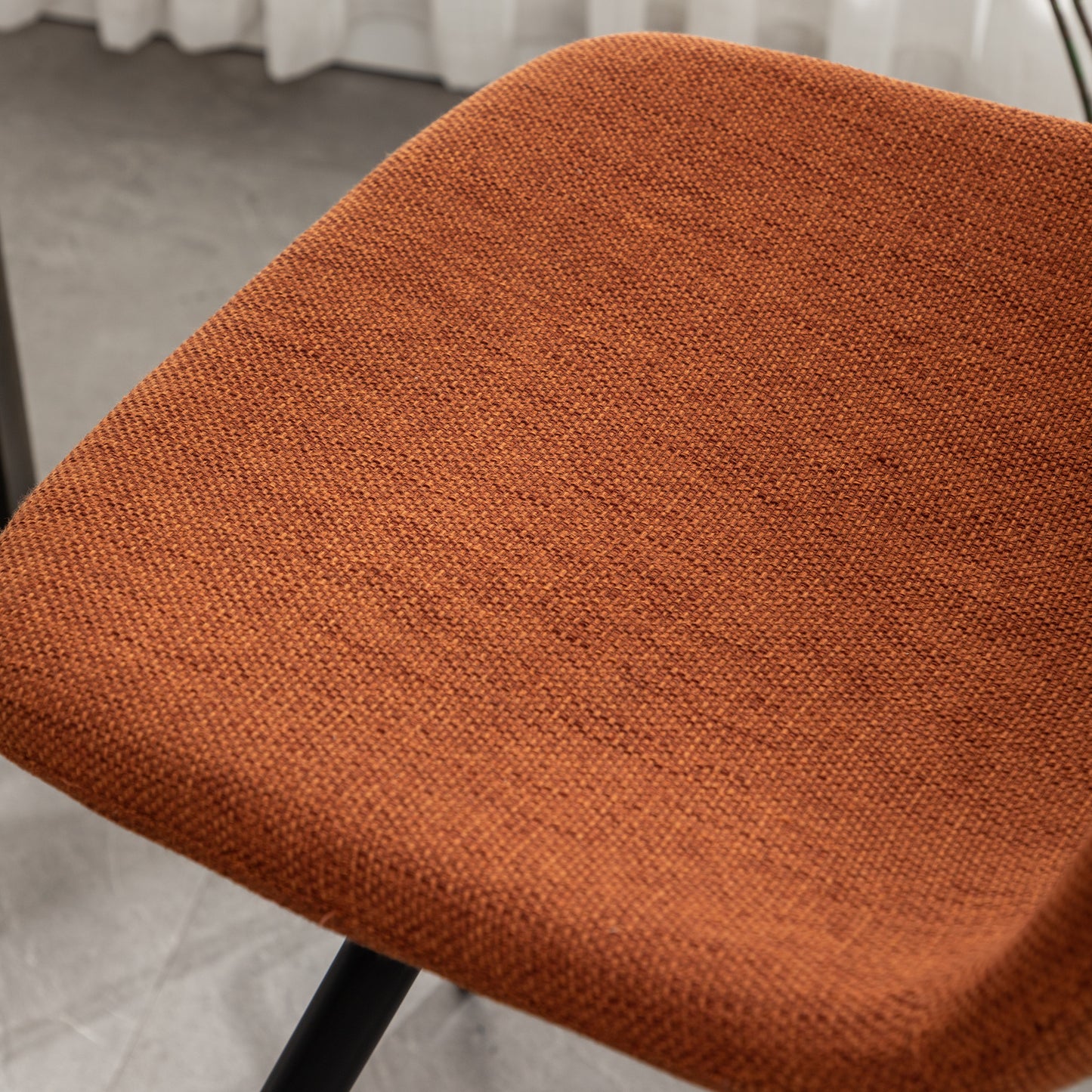 Closeup of a textured burnt orange fabric seat on a modern chair