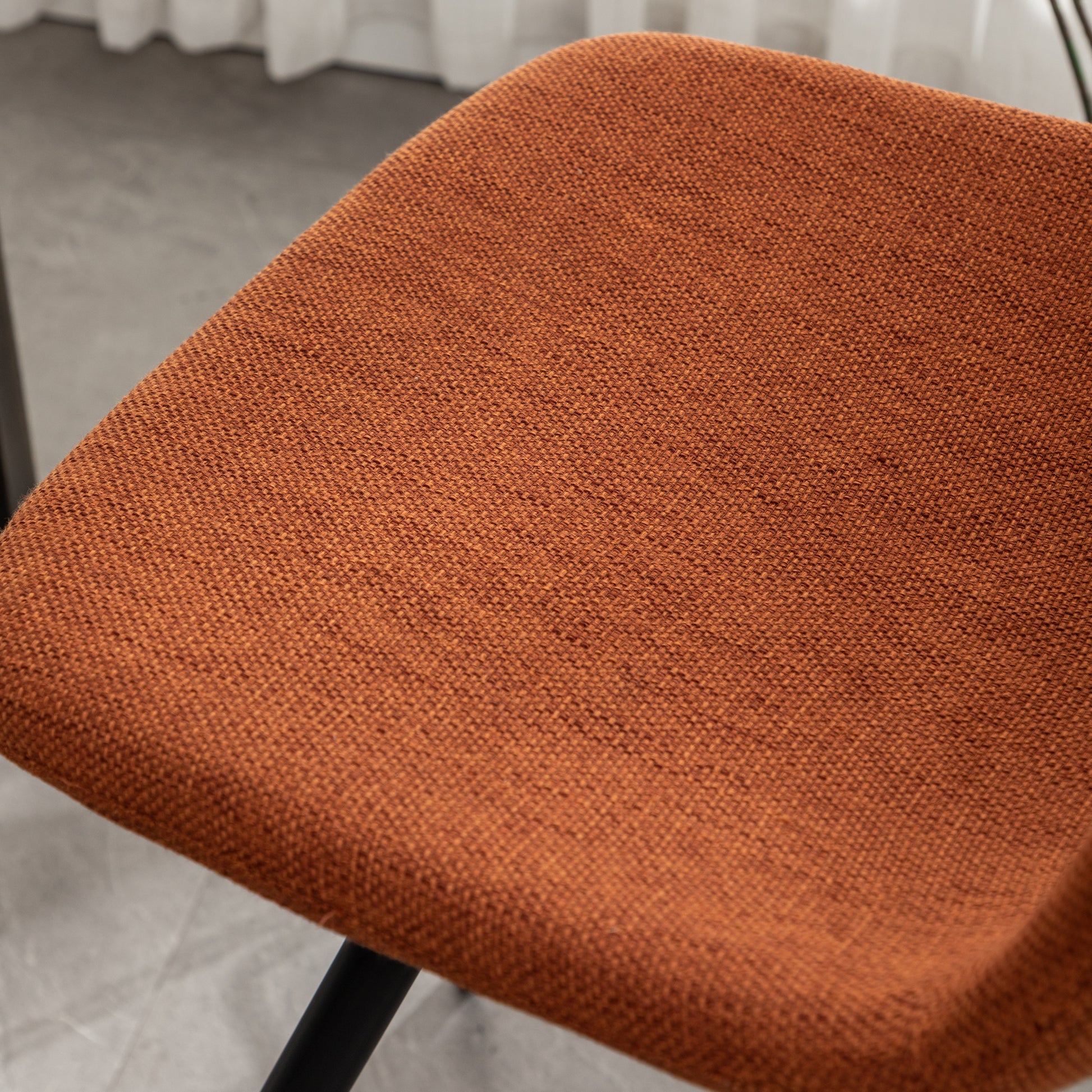 Closeup of a textured burnt orange fabric seat on a modern chair