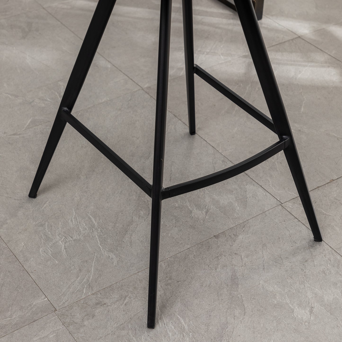 Black metal bar stool legs with footrest on stone tile floor