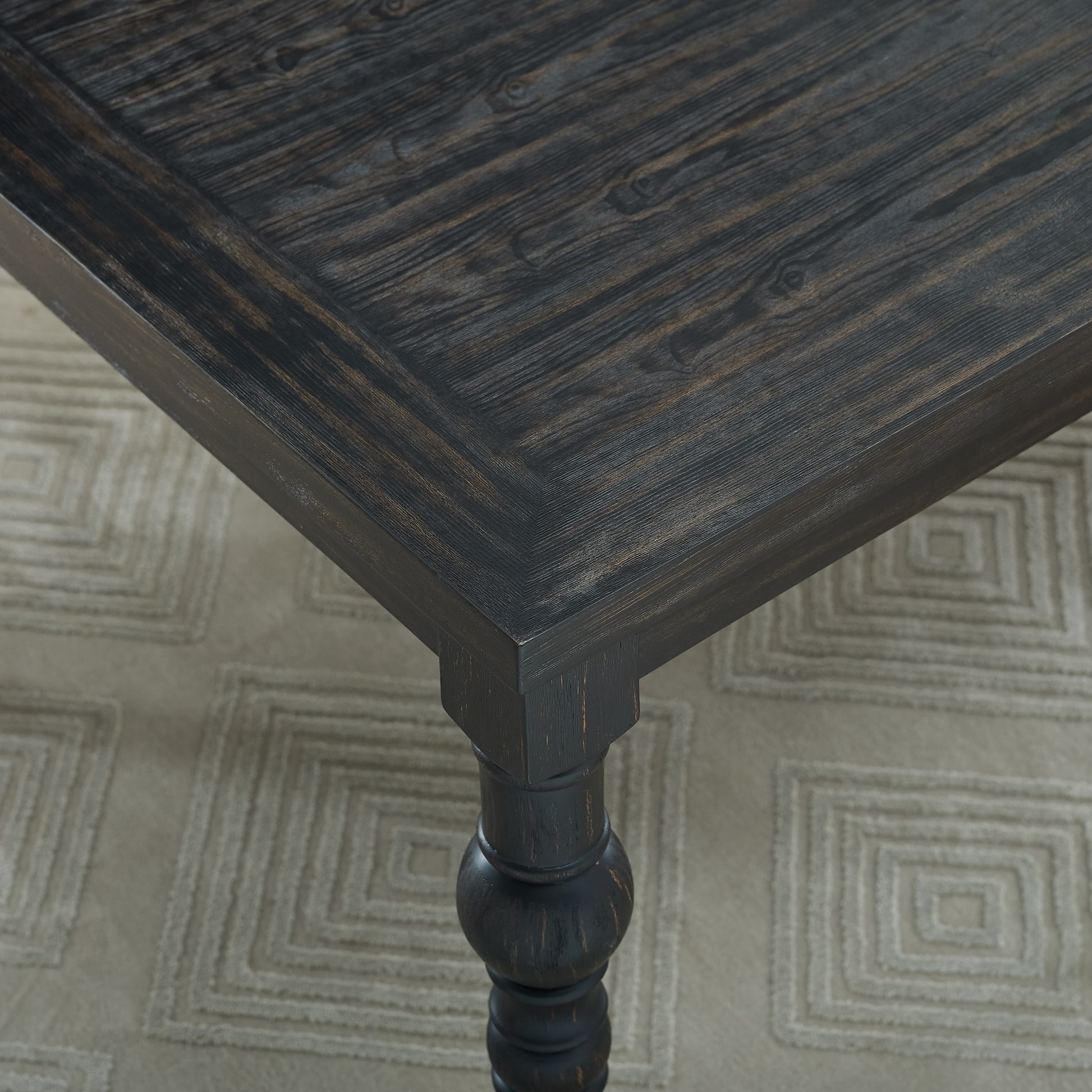 Dark wood dining table with textured grain and decorative turned leg
