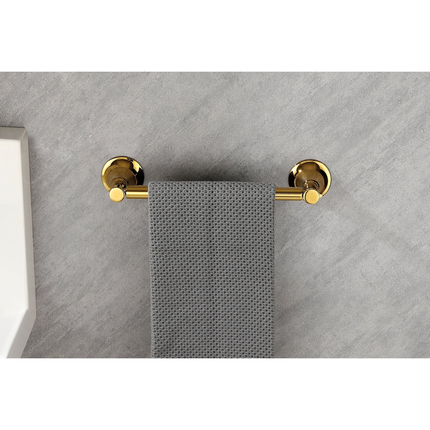 Polished brass wallmounted towel bar holding a gray waffleweave hand towel