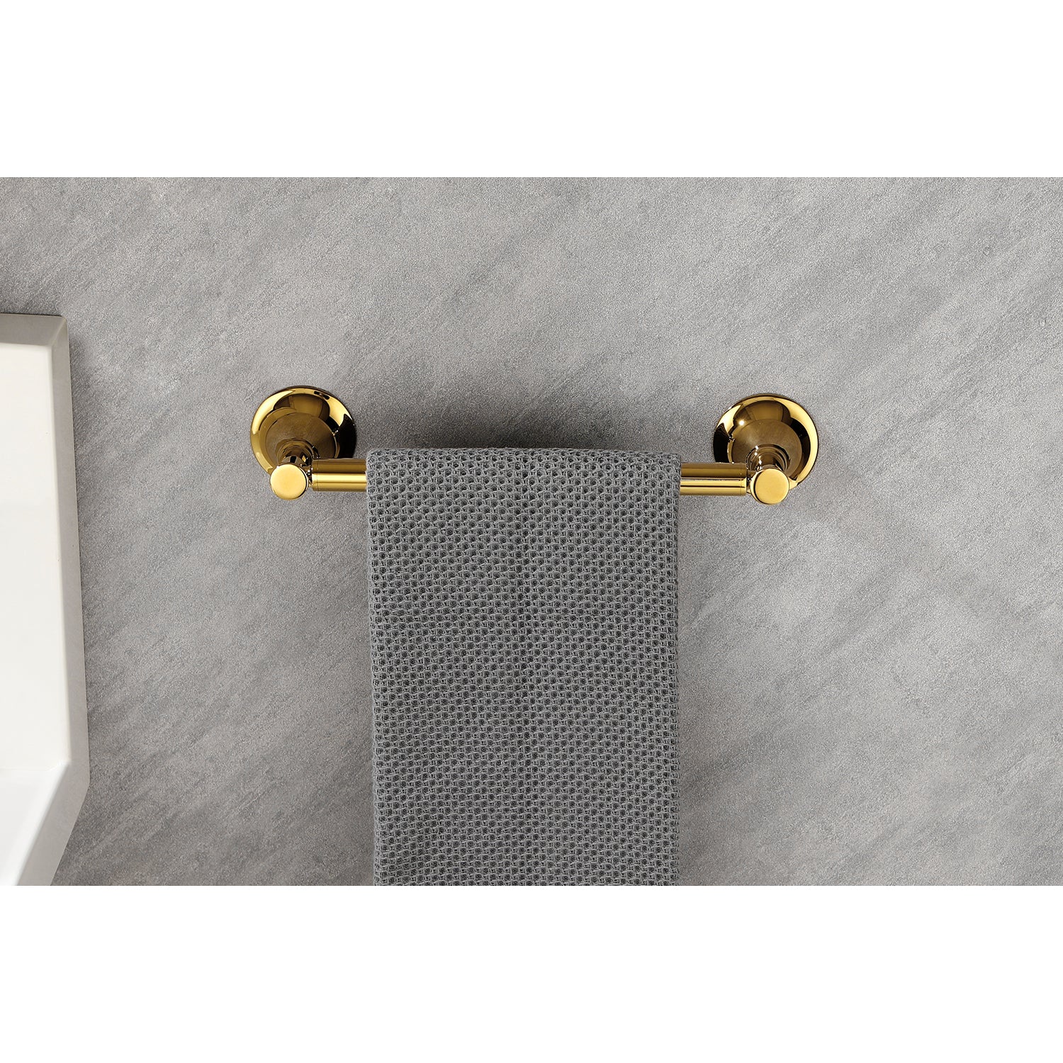 Polished brass wallmounted towel bar holding a gray waffleweave hand towel