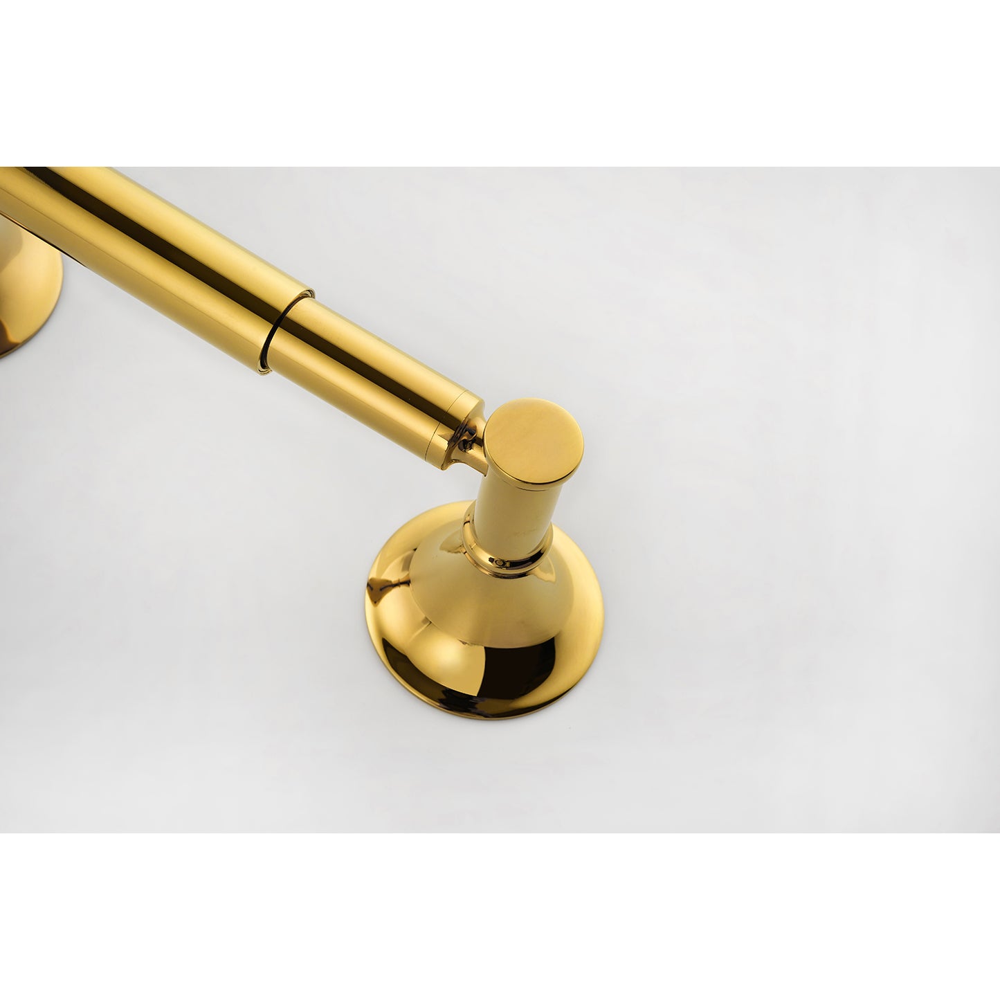 Polished brass toilet paper holder with a contemporary design mounted on a white surface
