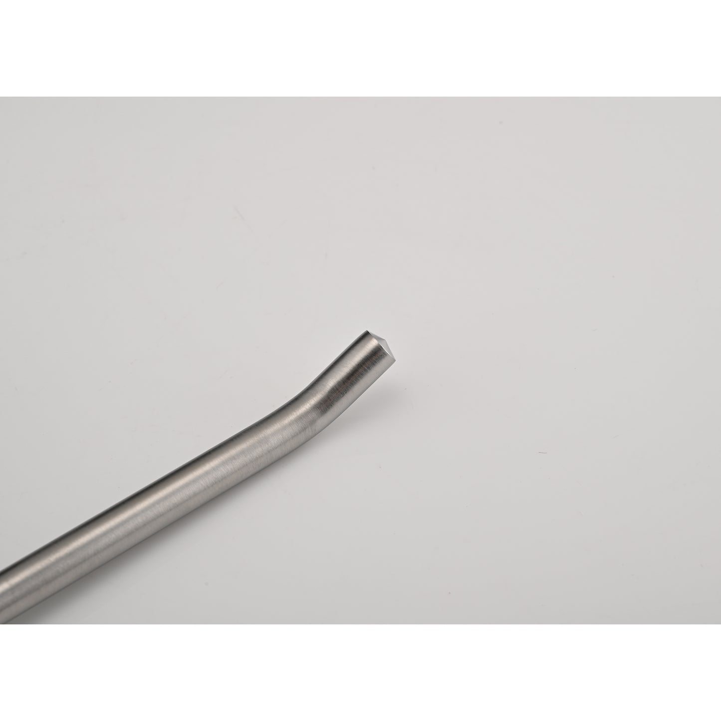 Closeup of a brushed stainless steel coffee stirrer with a curved handle