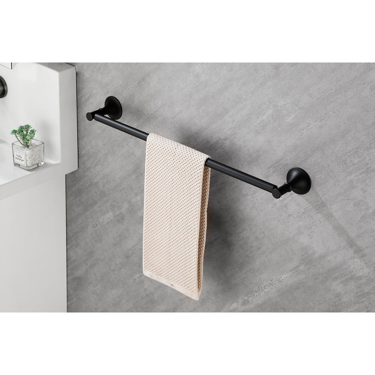 Black metal towel bar mounted on a grey tiled wall holding a cream textured towel