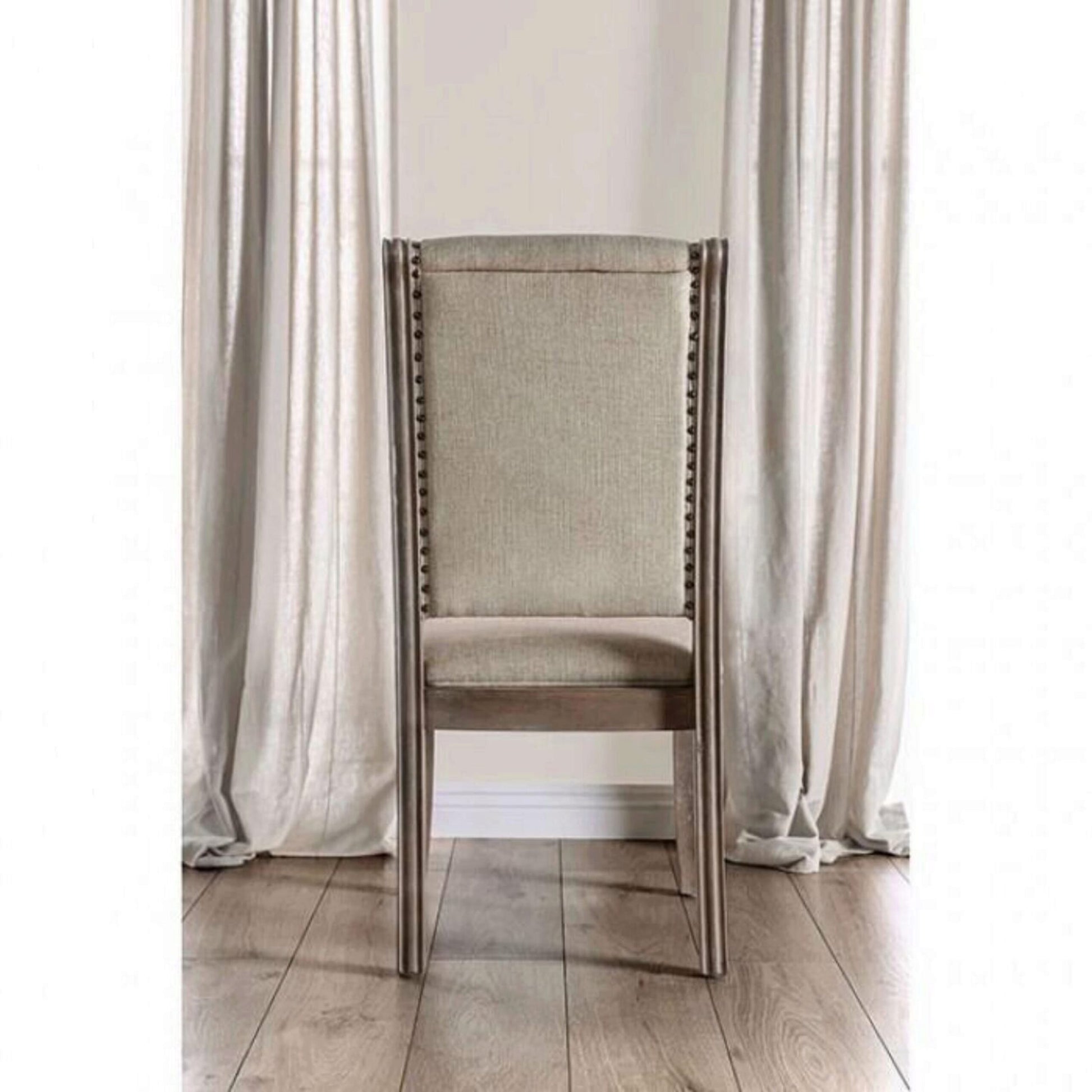 Tall upholstered dining chair in beige linen with studded trim and dark wood frame