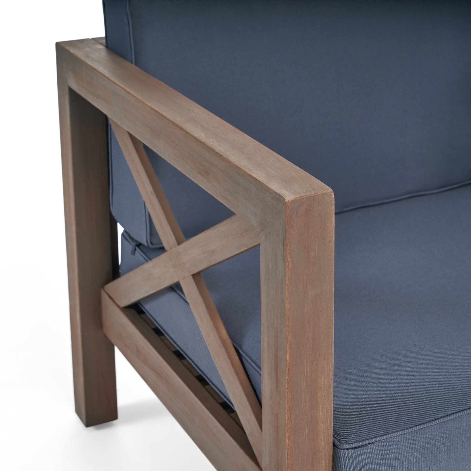 Closeup of a wooden armchair armrest with xdesign featuring navy blue cushion