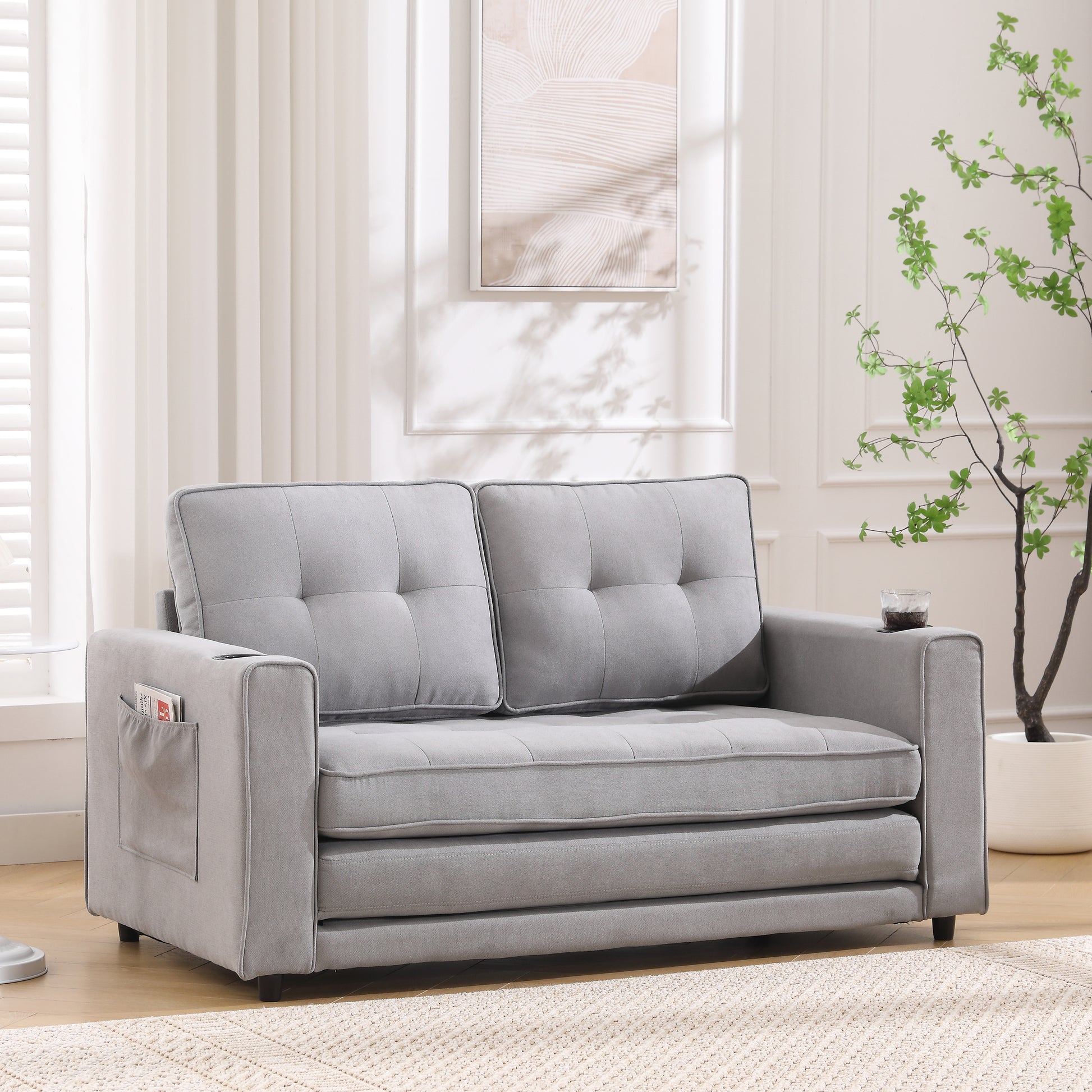 Grey upholstered loveseat with tufted cushions and side storage pocket