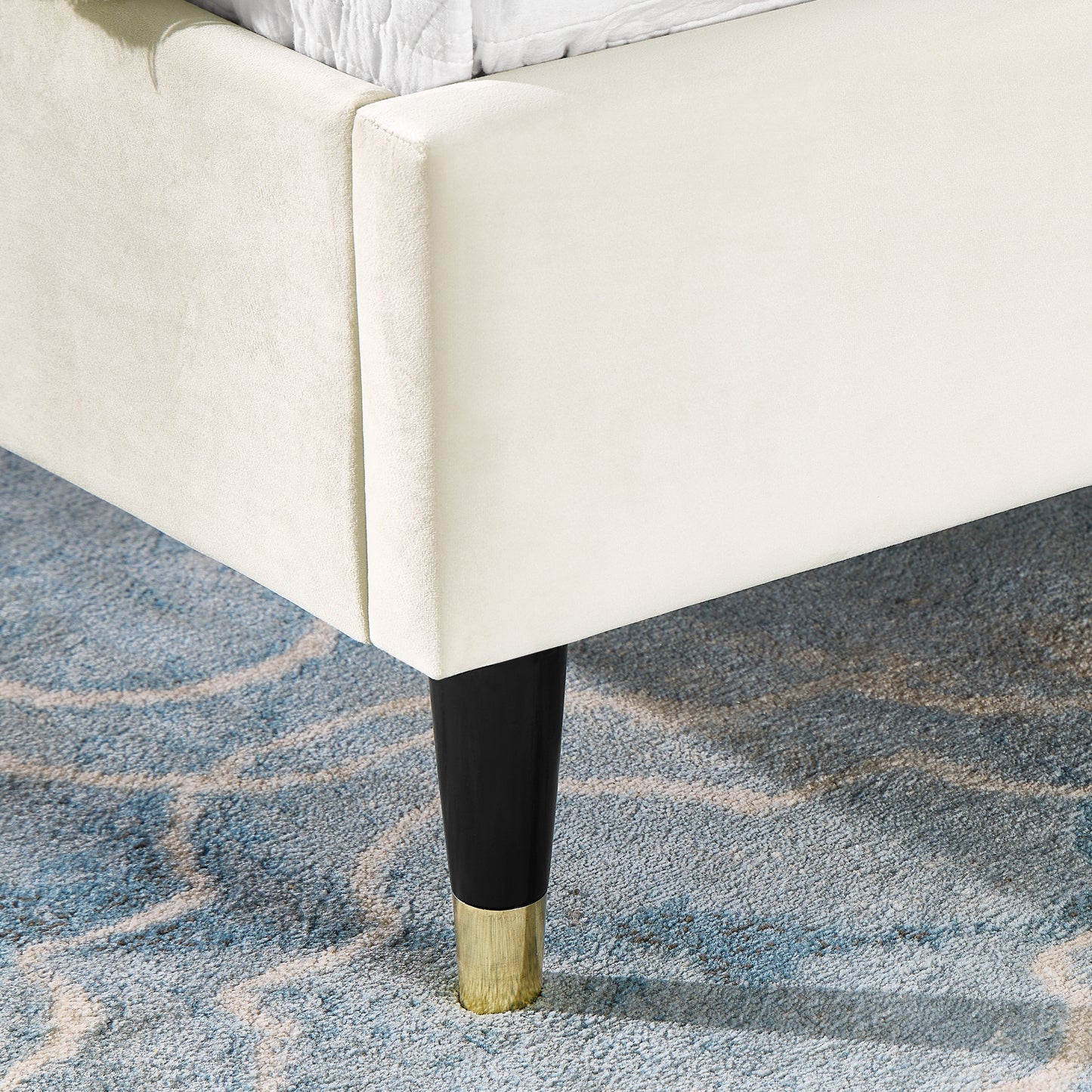 Cream velvet bed frame detail with black and gold leg