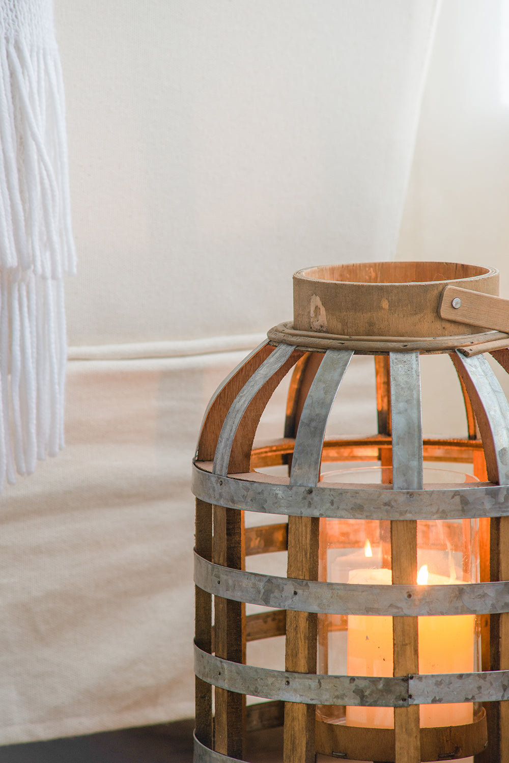 Rustic wooden and metal lantern with glass cylinder holding lit candles