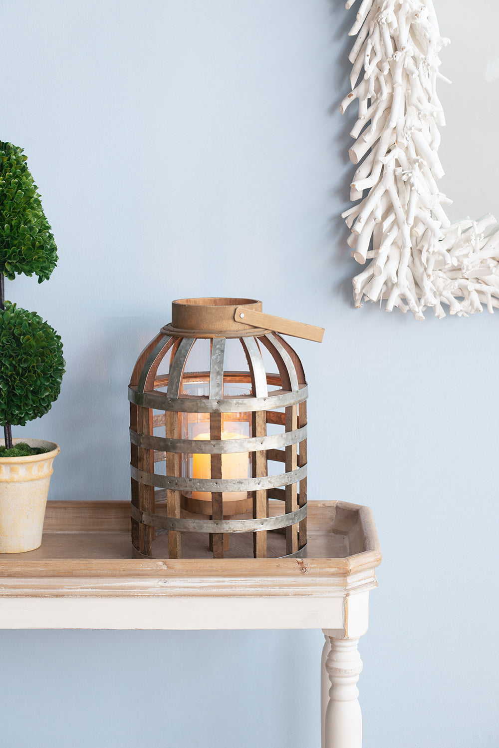 Rustic wooden lantern with metal bands and a lit pillar candle inside