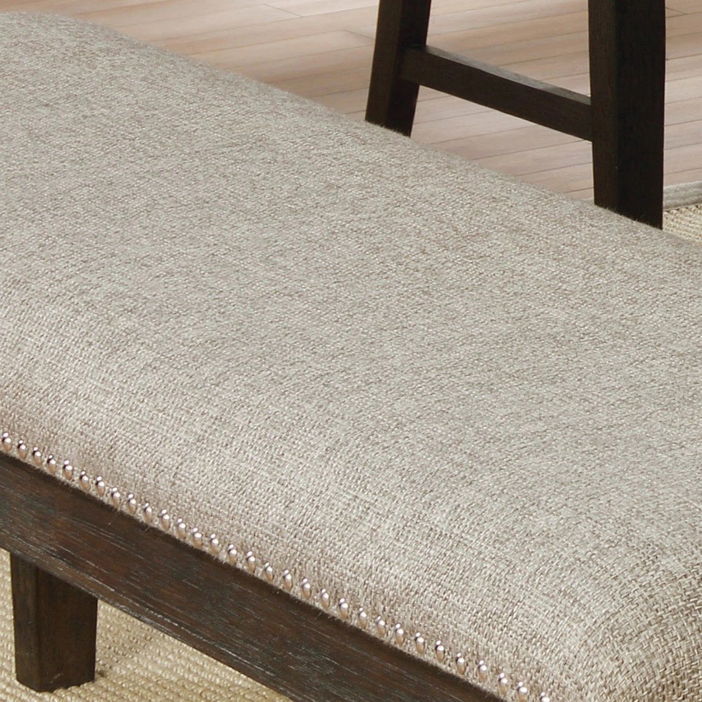 Beige upholstered dining bench with dark wood trim and nailhead accents