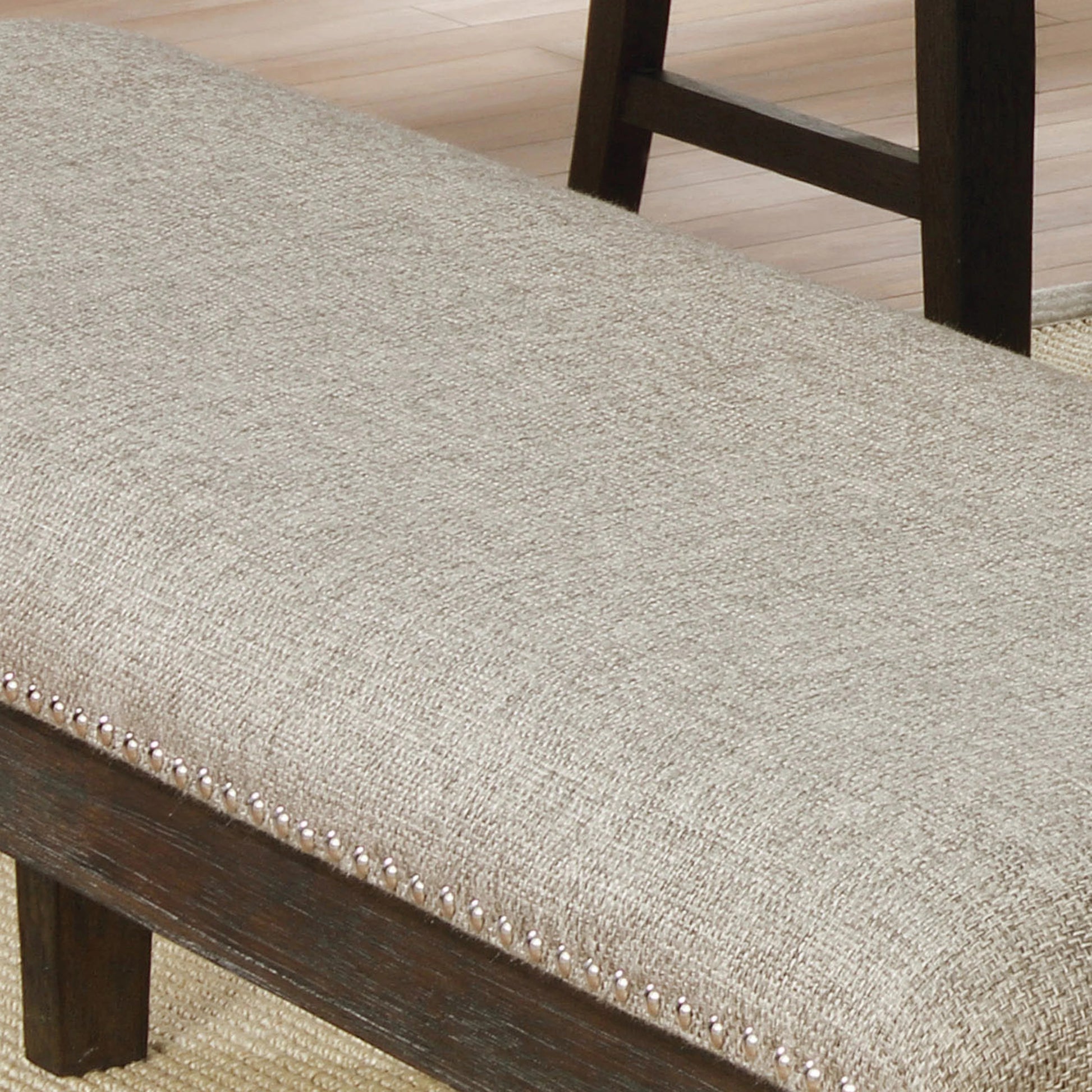 Beige upholstered dining bench with dark wood trim and nailhead accents