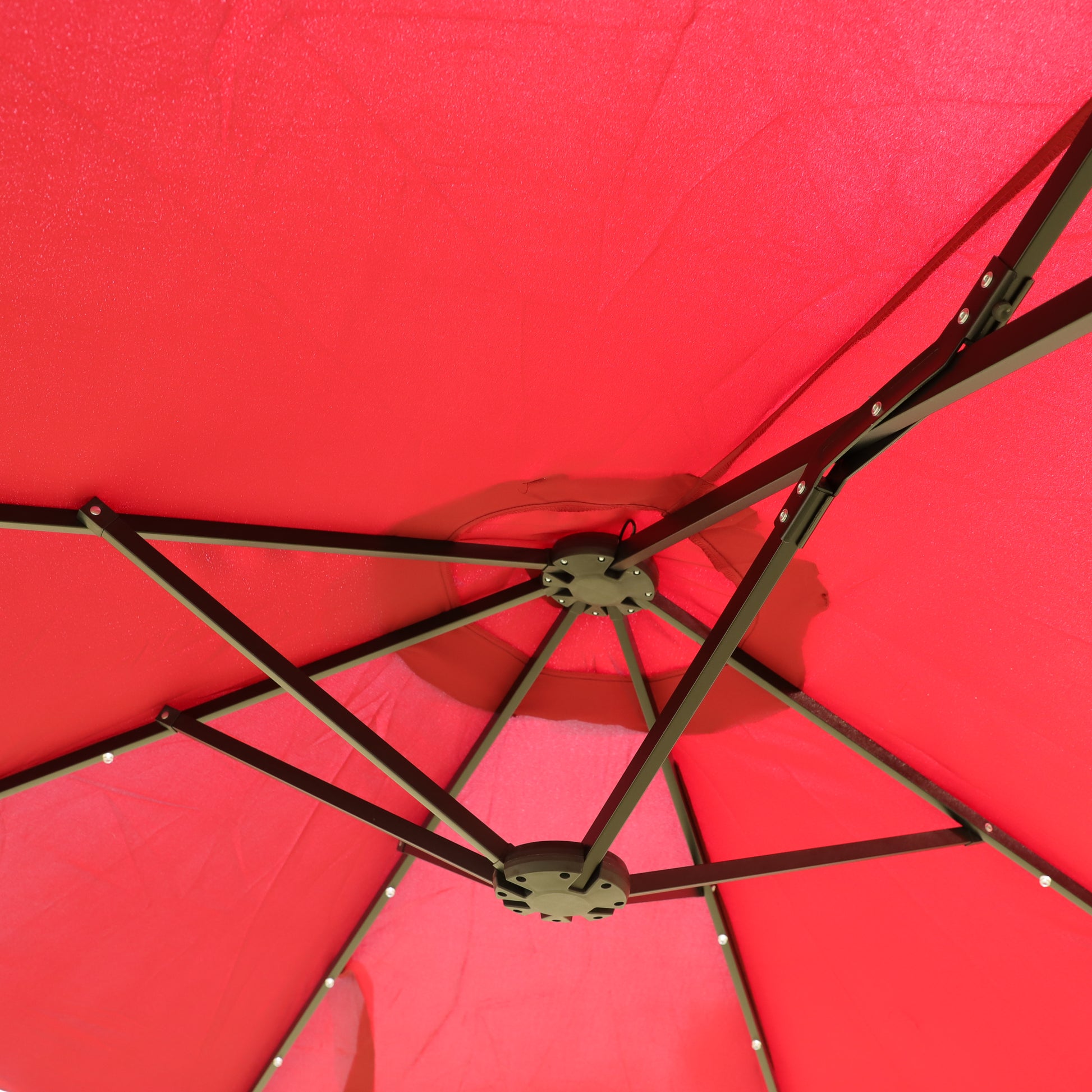 Closeup view of the underside of a red canopy tent highlighting the dark metal frame construction and fabric material
