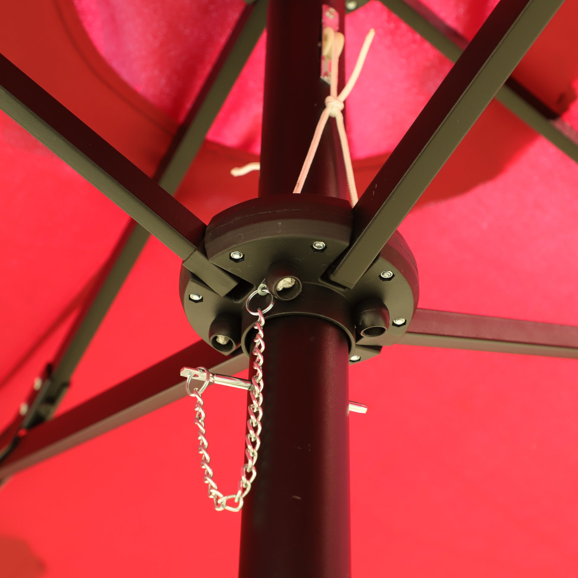 Red patio umbrella mechanism with black metal frame and silver chain