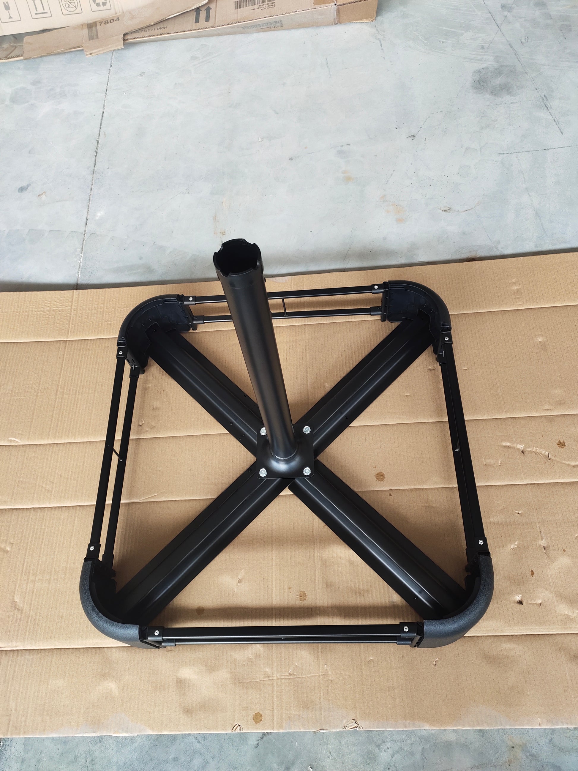 Black metal umbrella base frame with a central pole ideal for patio outdoor use