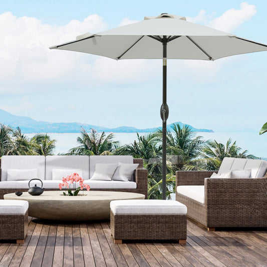 White patio umbrella with dark pole set on a wooden deck with wicker furniture