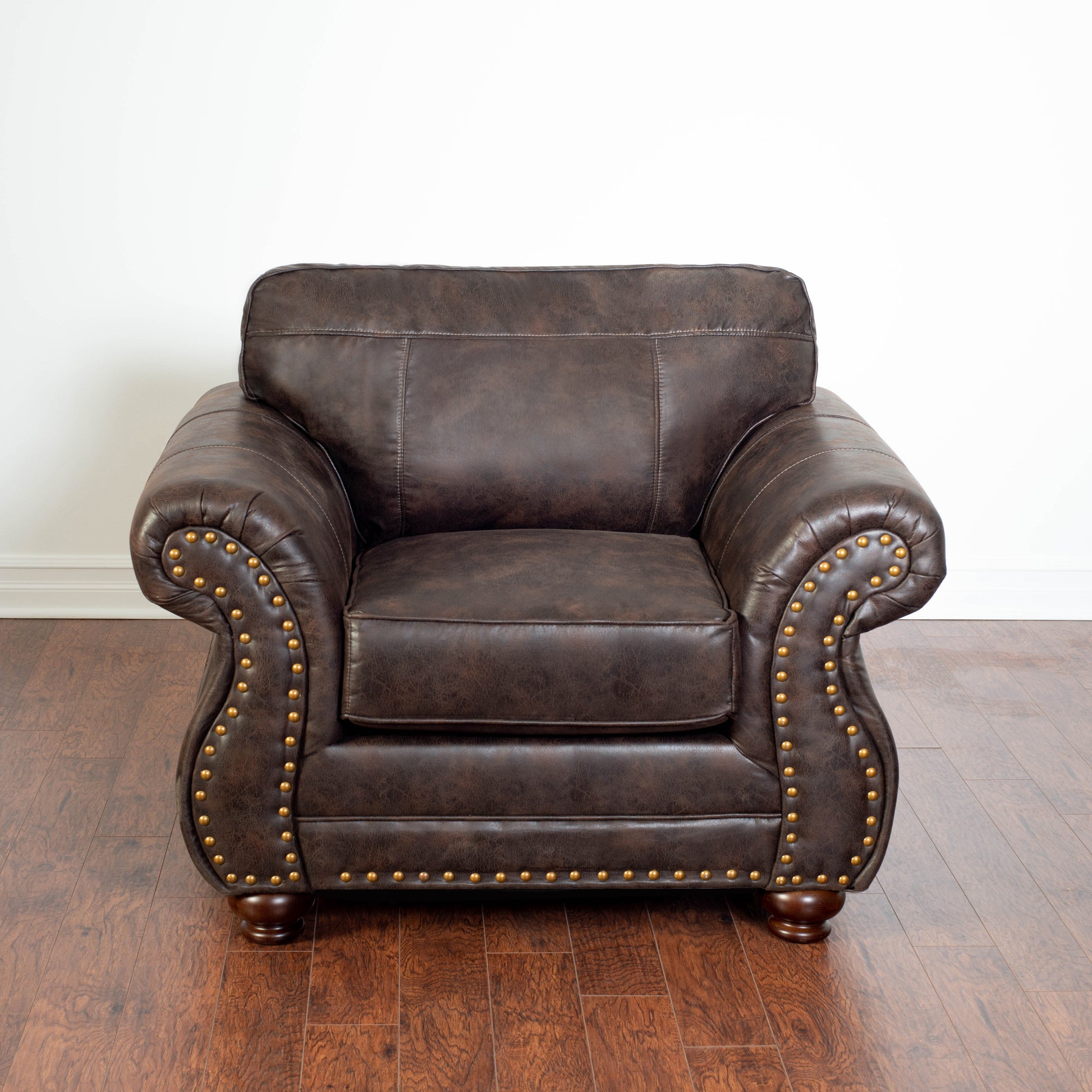A distressed brown leather armchair with gold nailhead trim offers classic comfort