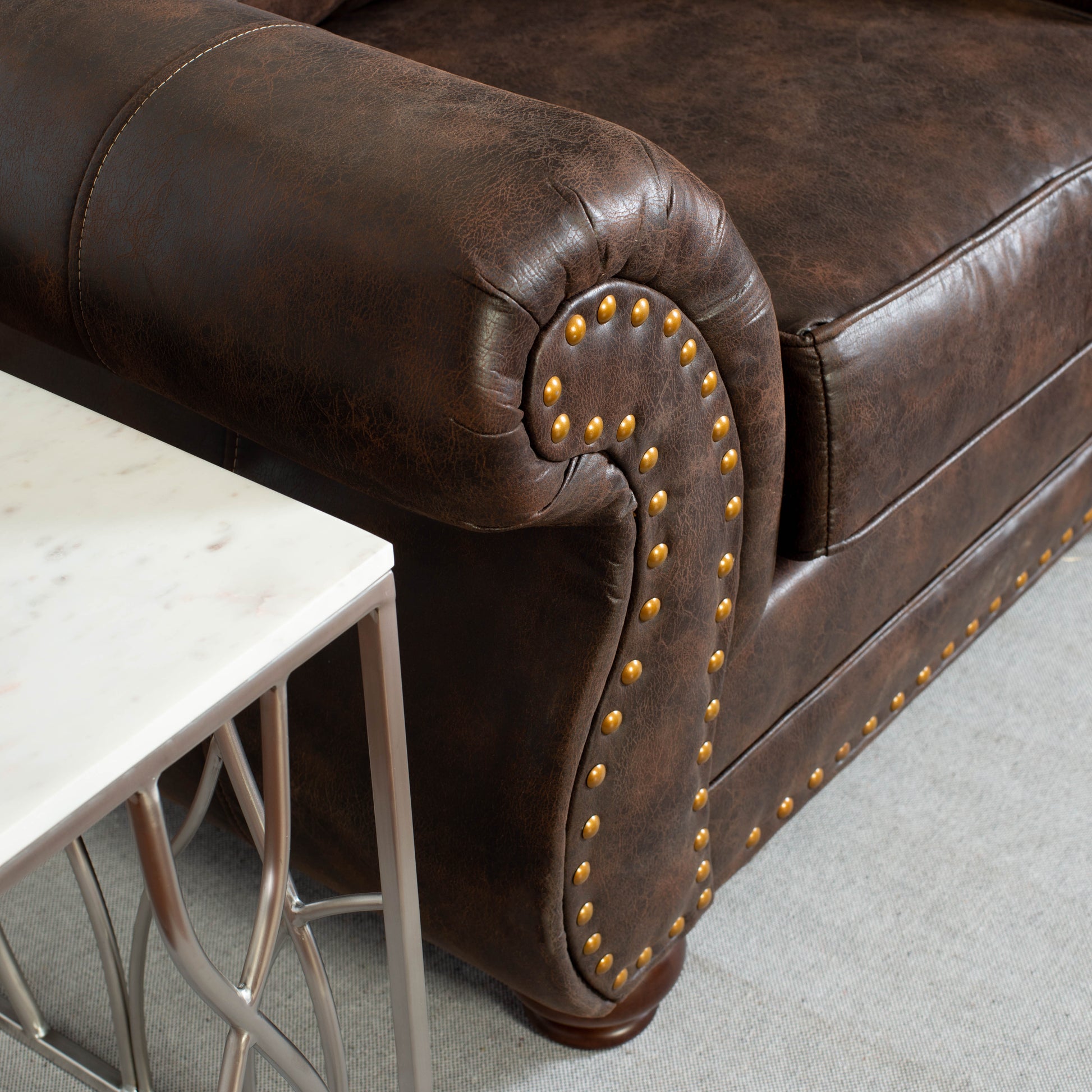 Dark brown leather chesterfield armchair with decorative brass nailhead trim detailing