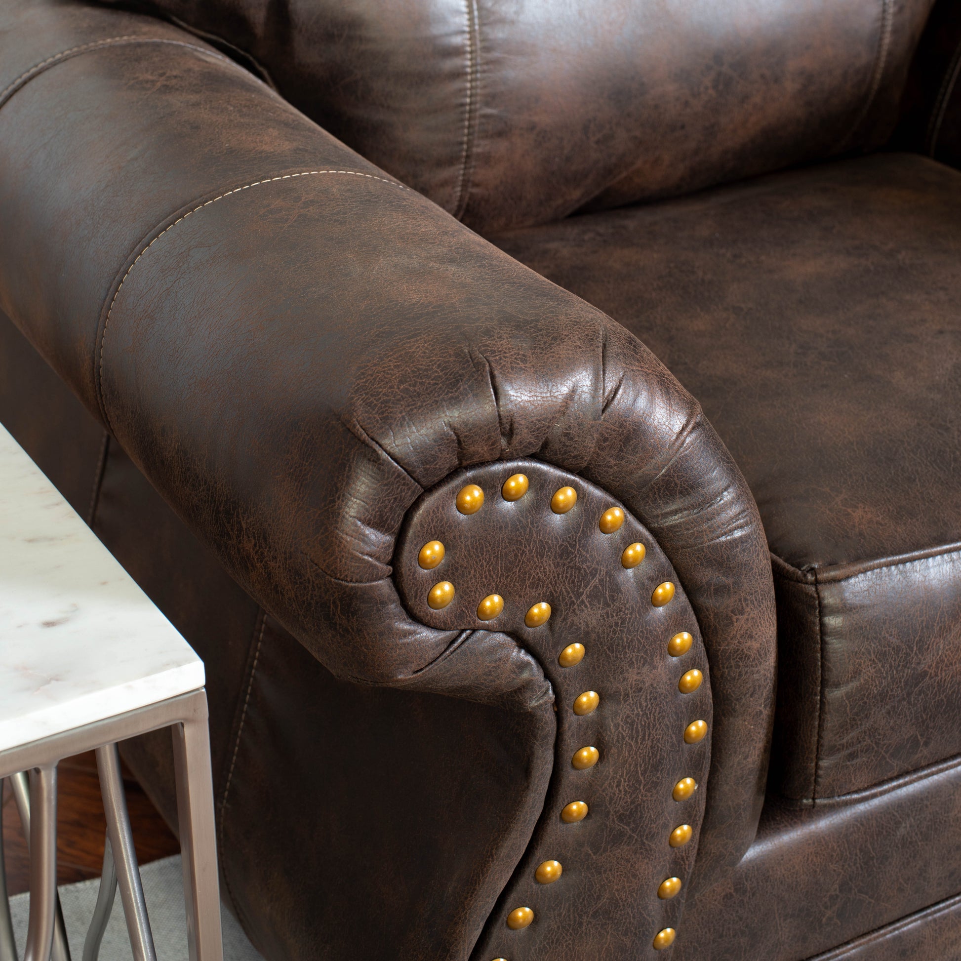 Dark brown leather armchair armrest with brass nailhead trim detail