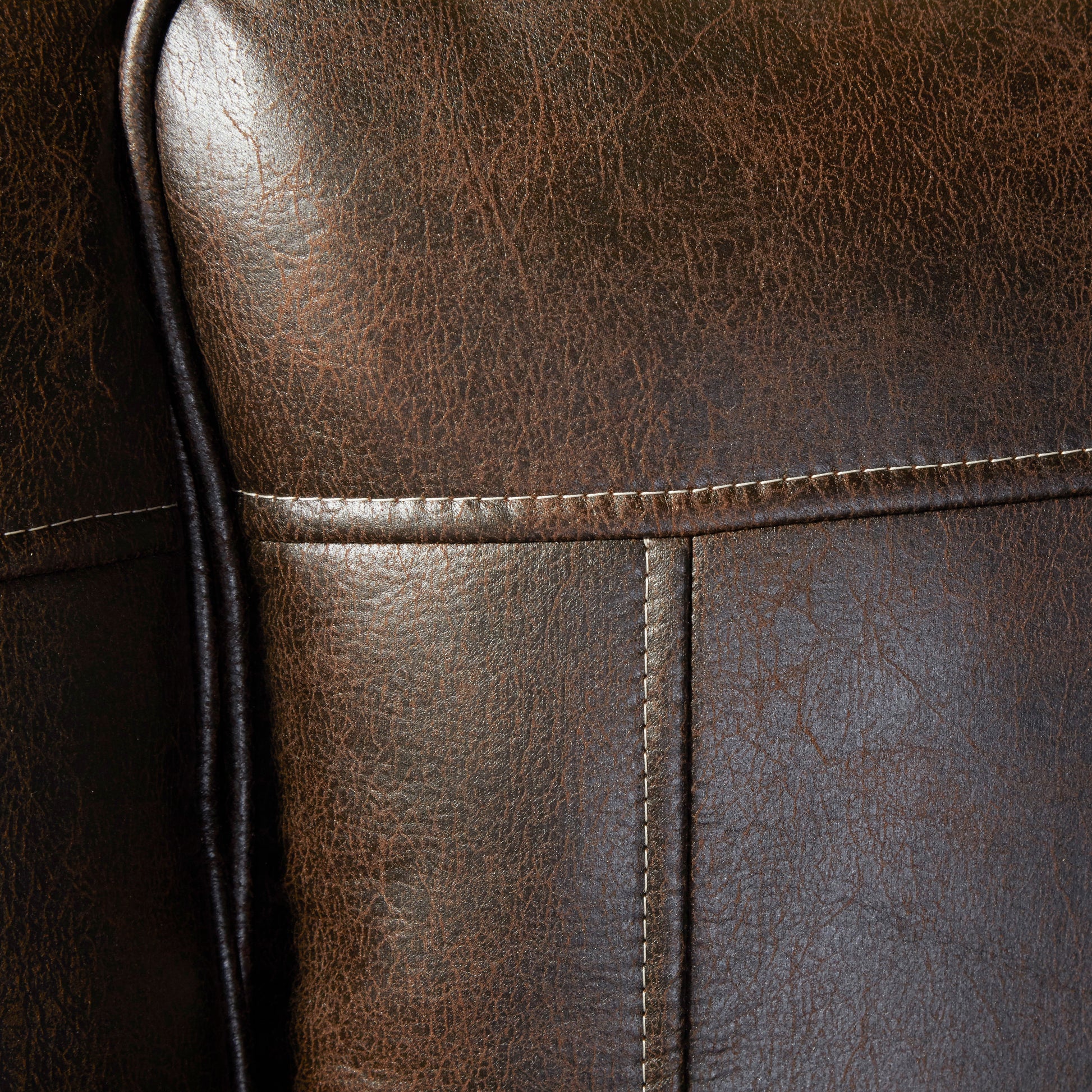 Closeup of rich brown distressed leather upholstery with cream stitching detail