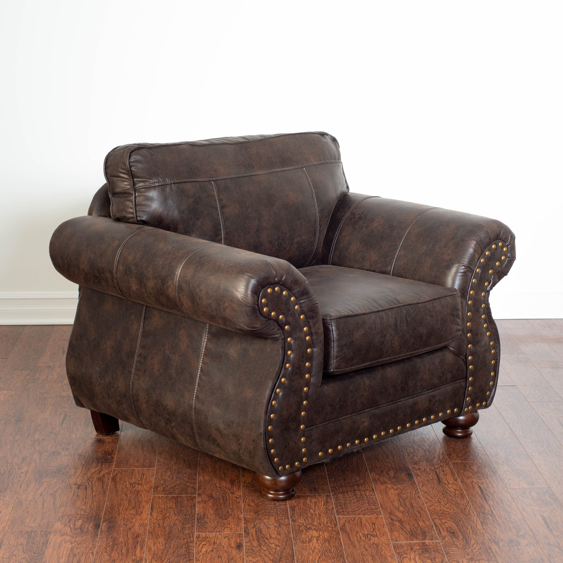 Dark brown distressed leather armchair with brass stud accents and white stitching