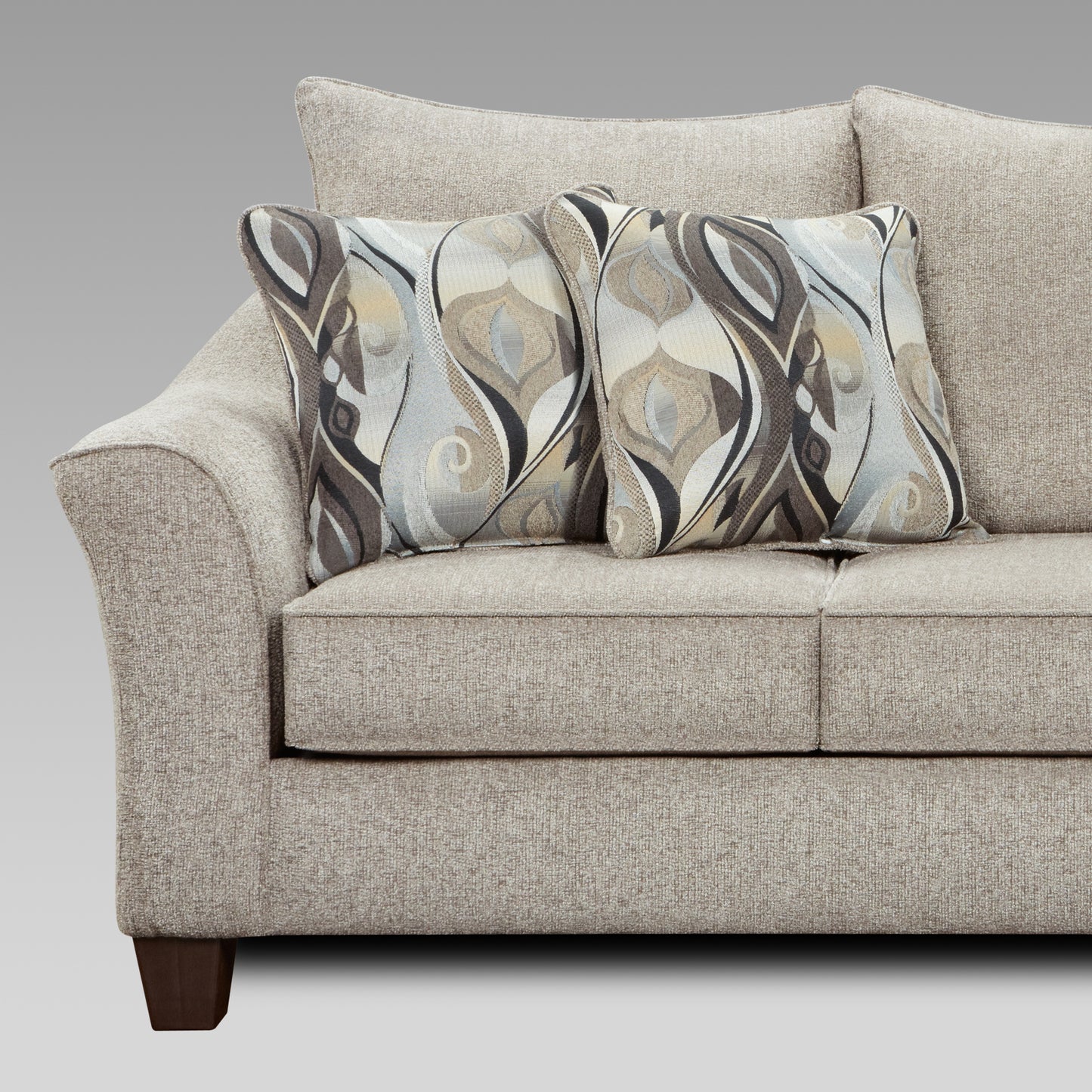 Closeup of a beige sofa with two decorative throw pillows featuring a brown and blue abstract pattern