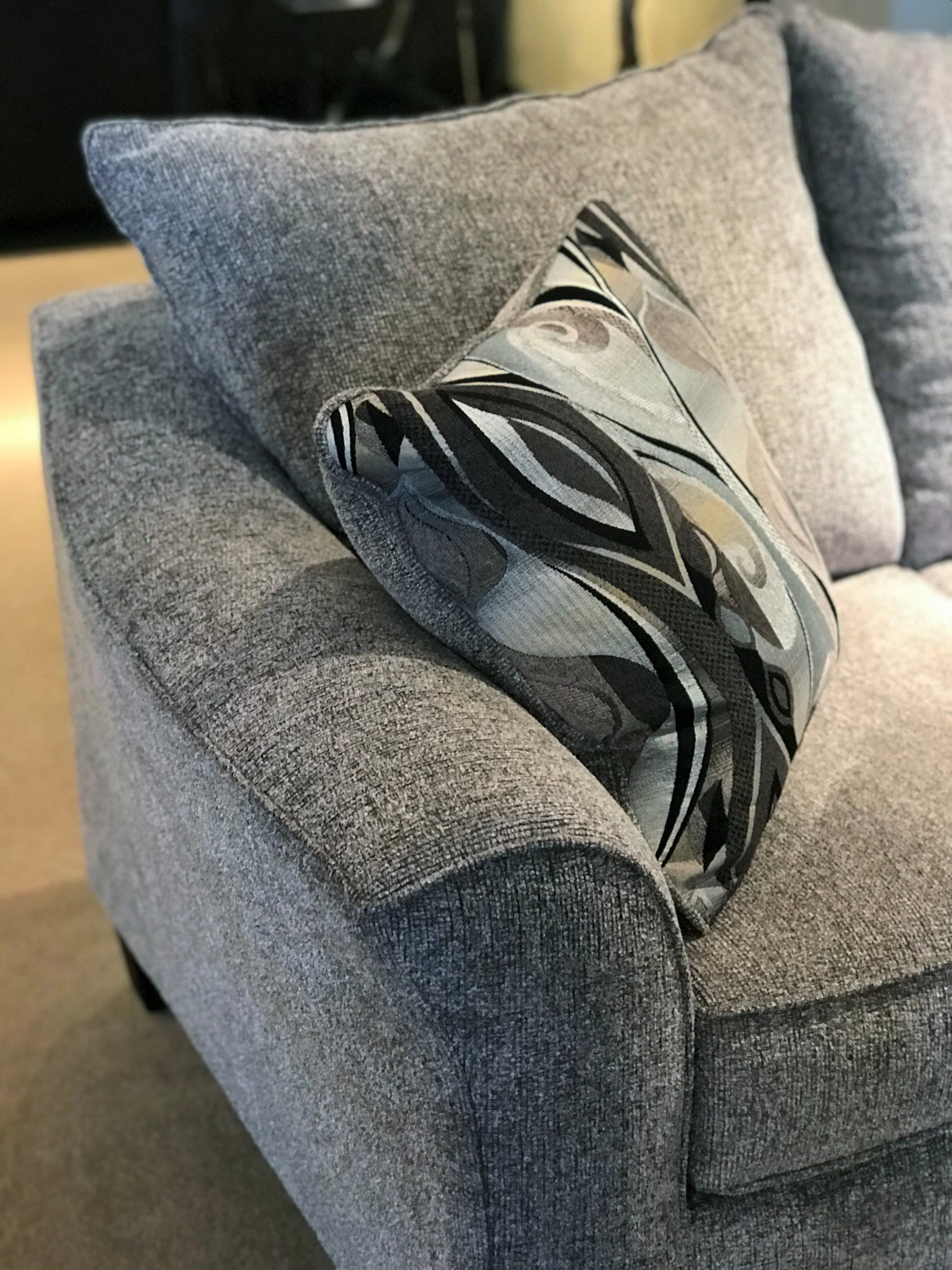 Gray fabric sofa with a decorative throw pillow featuring abstract black and white patterns