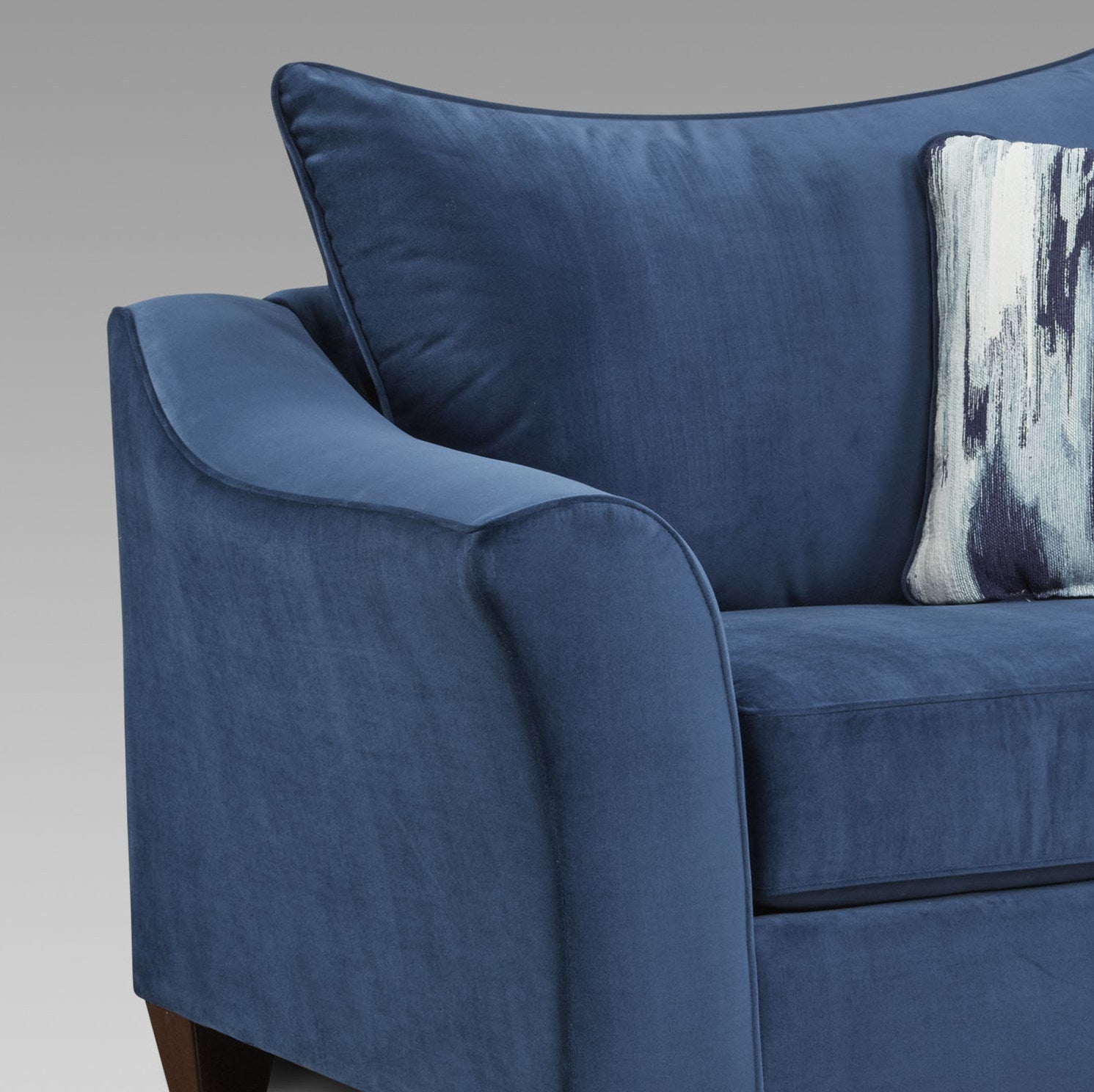 Navy blue velvet armchair with plush cushions and decorative throw pillow