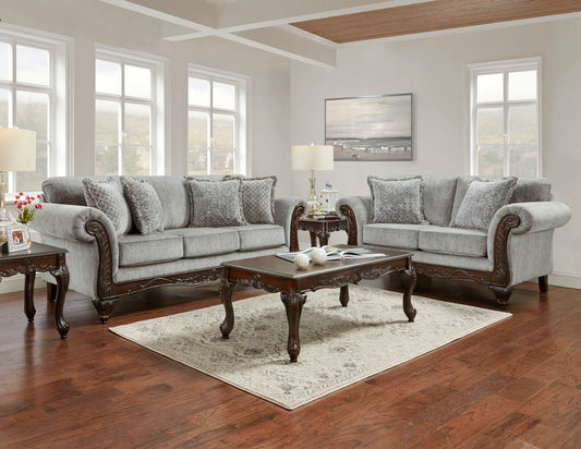 Luxurious grey fabric sofa with ornate dark wood accents and patterned throw pillows for elegant living room seating