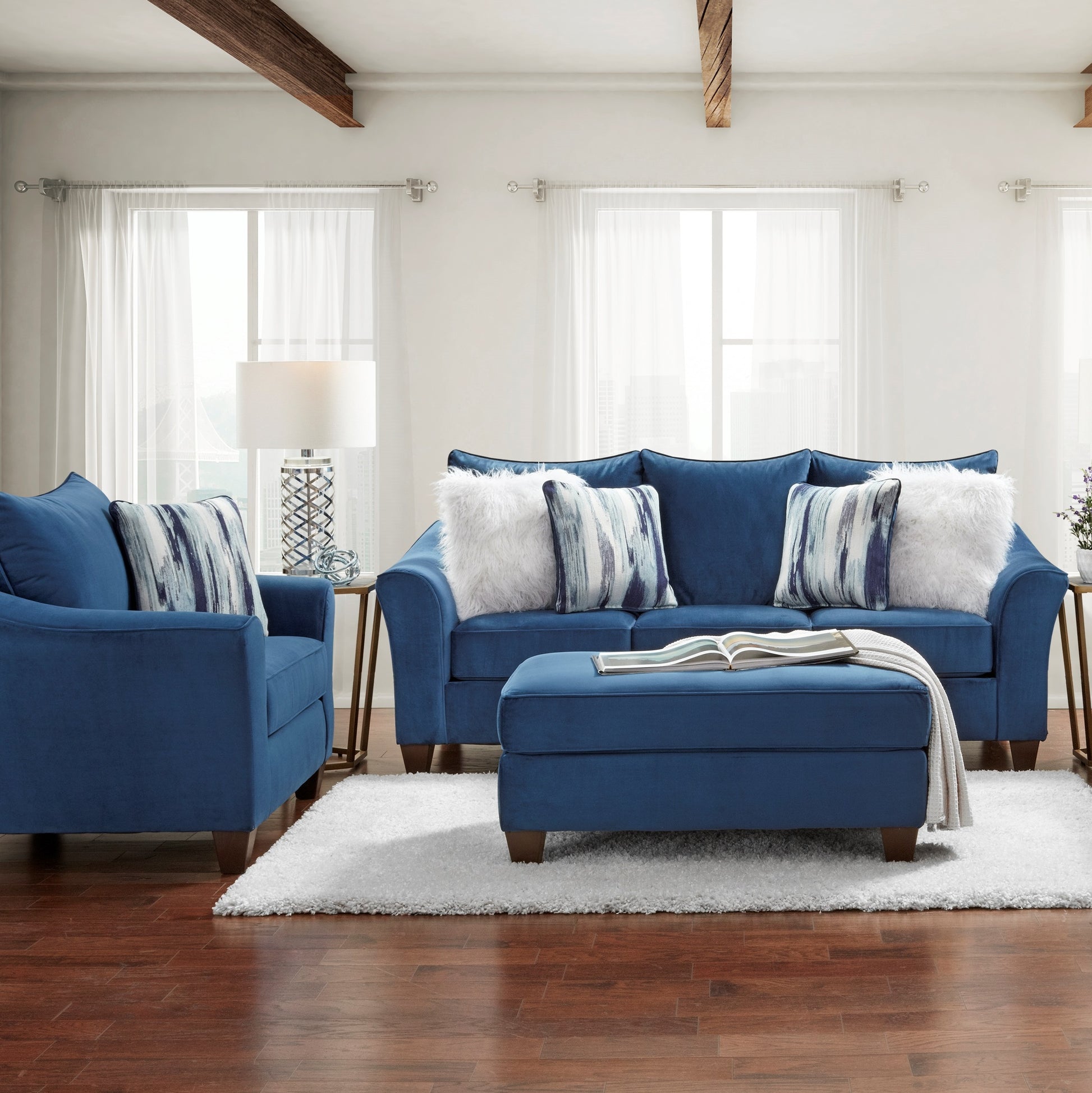 Deep blue velvet sofa with decorative pillows and matching ottoman