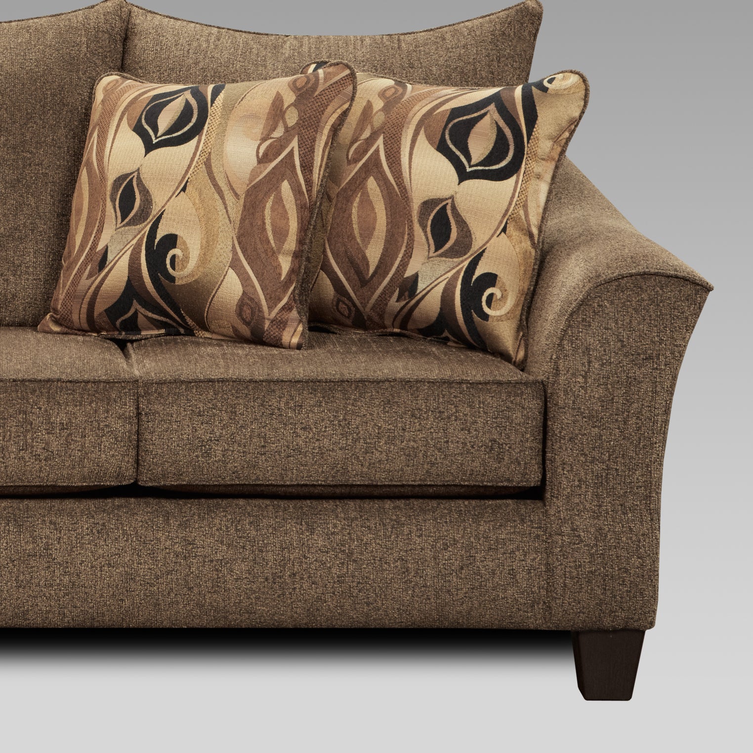 Closeup of a brown textured fabric sofa with two throw pillows featuring a brown black and tan abstract floral pattern