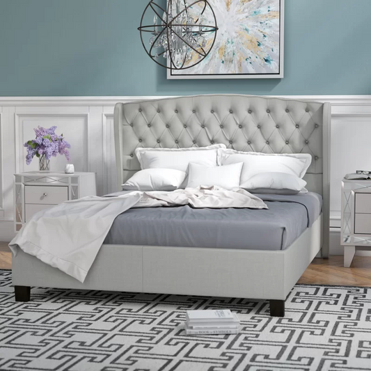 Light gray upholstered wingback bed with button tufting and white bedding