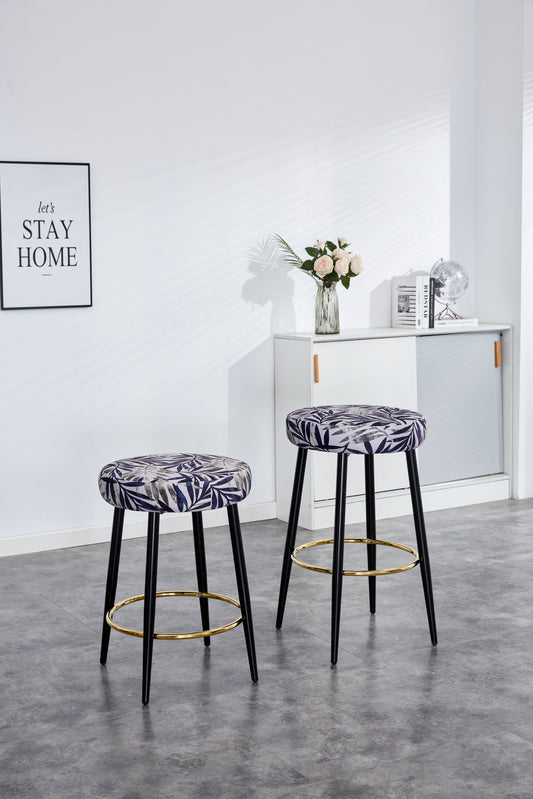 Two modern bar stools with blue leaf pattern upholstery and gold footrests