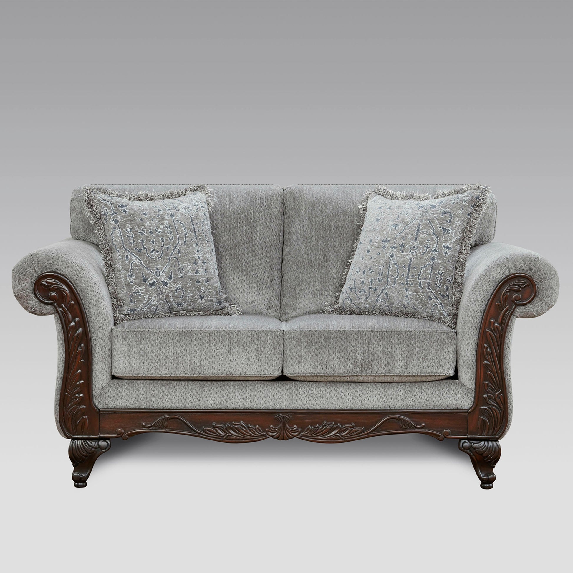 Gray upholstered loveseat with ornate dark wood trim and decorative throw pillows