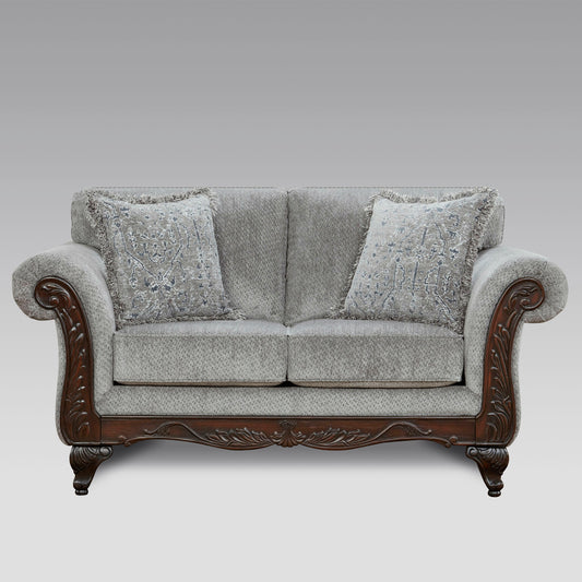 Gray upholstered loveseat with ornate dark wood trim and decorative throw pillows