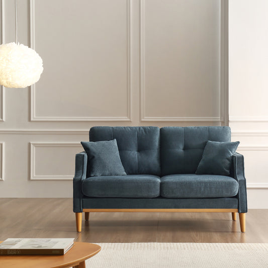 Tufted navy blue fabric sofa with wooden legs and two throw pillows for living room comfort