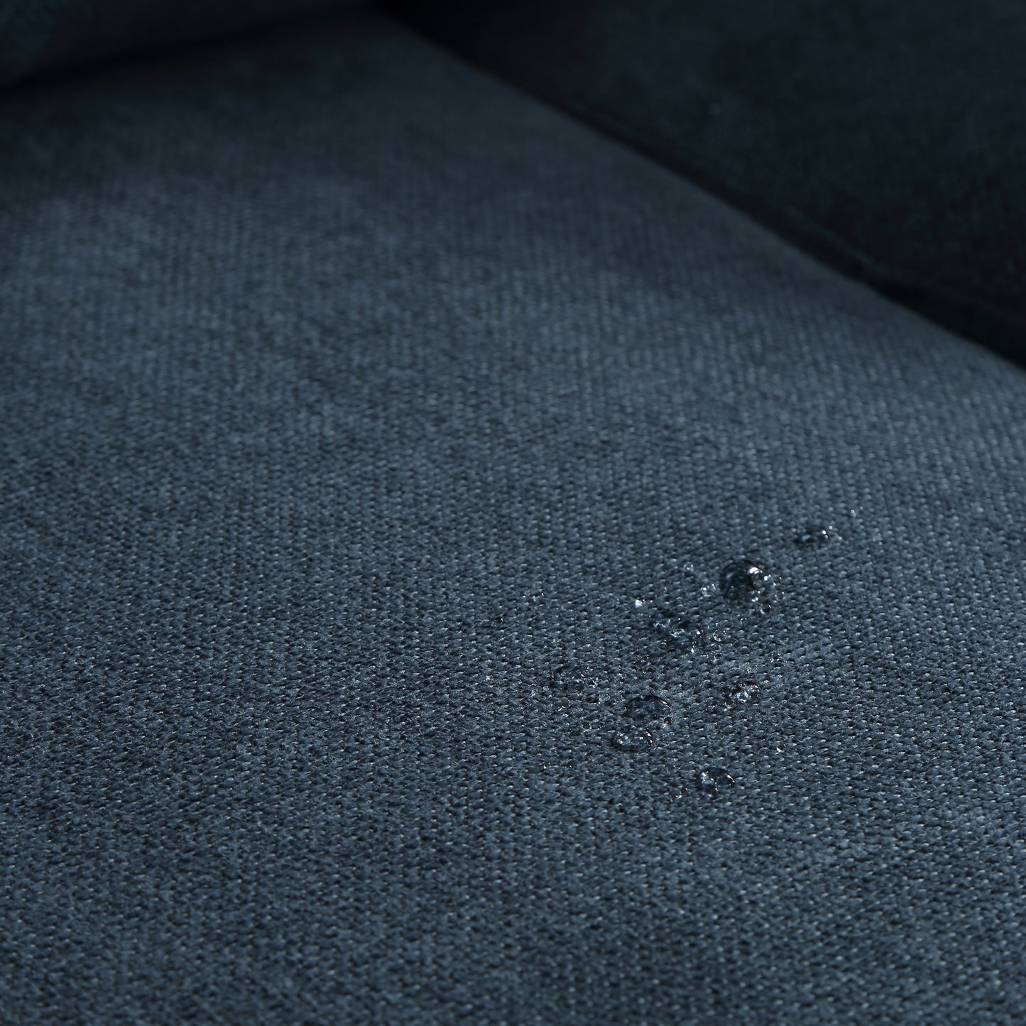 Dark blue woven fabric showing water beading indicating a waterproof material for upholstery